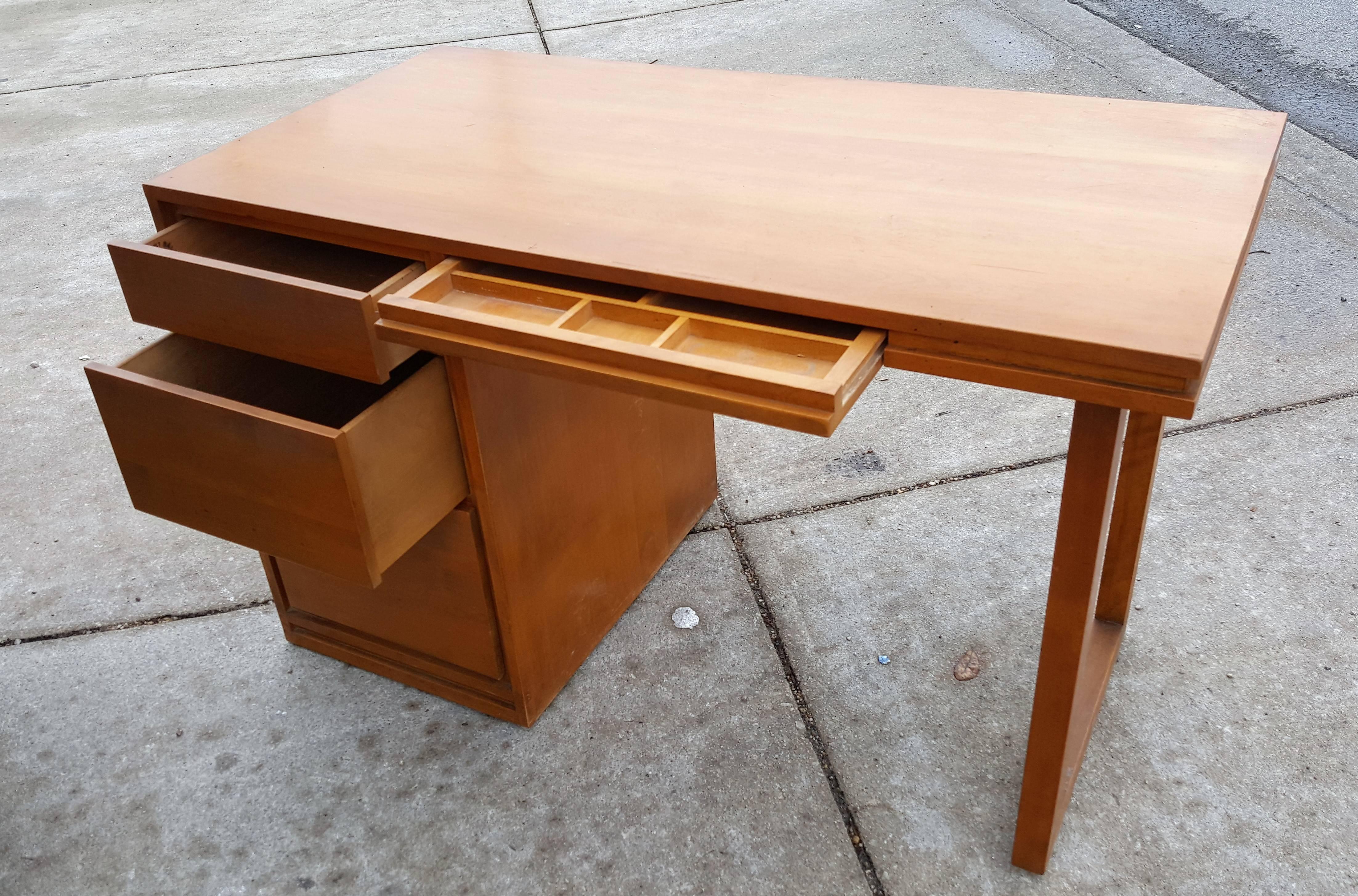 Russel Wright for Conant Ball company Mid-Century Modern solid birch desk from the 1950s Modernmates Line. The desk has a solid left side with three gradient sized drawers, convenient center drawer with organized compartments and open support to the