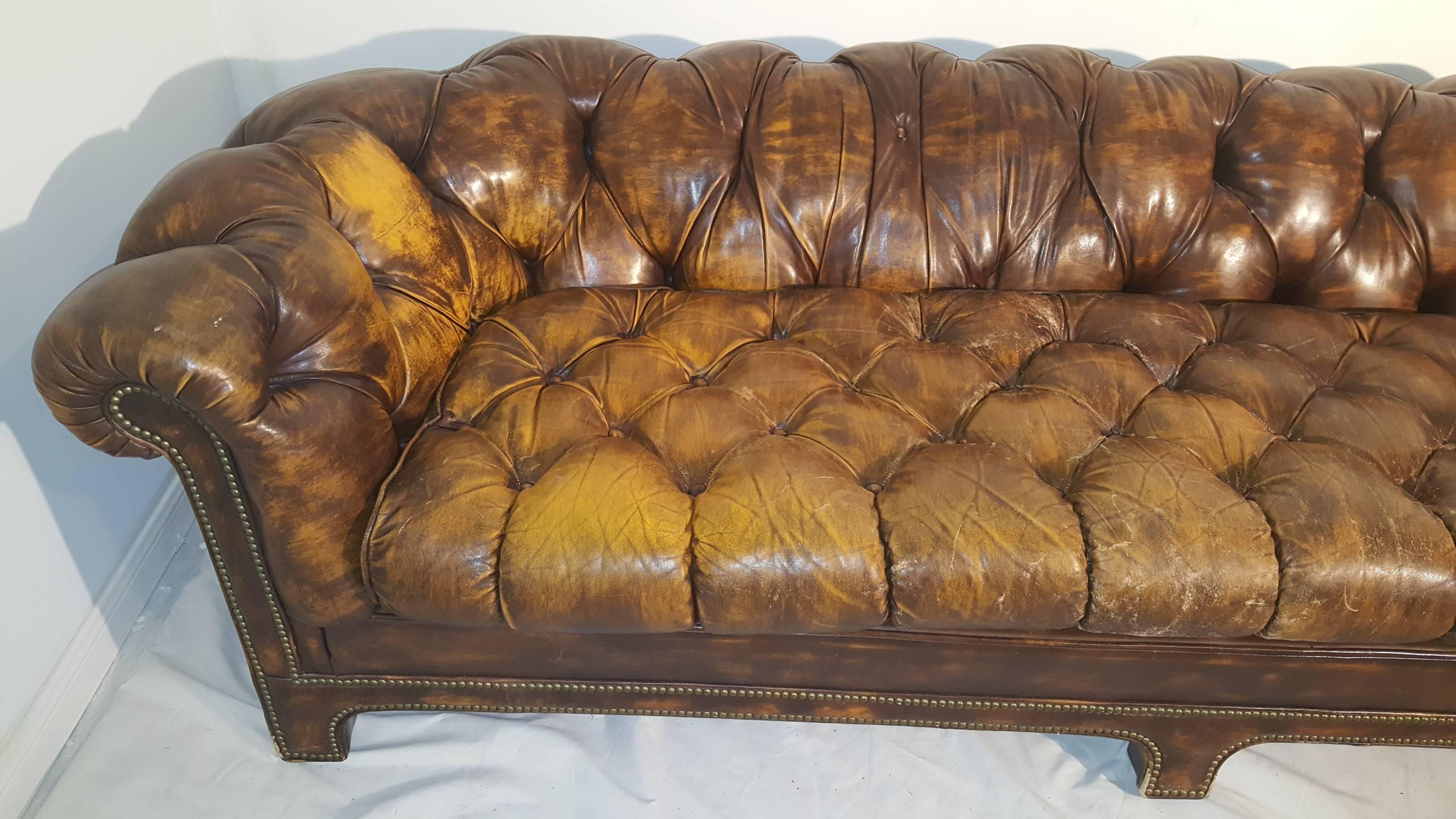 Distressed brown leather sofa designed by Ralph Morse in Grand Rapids. Worn beautifully, the tufted sofa has nailheads outlining base and is comfortable and perfect for a den or study. Provenance underside couch. Small tear that can be repaired on