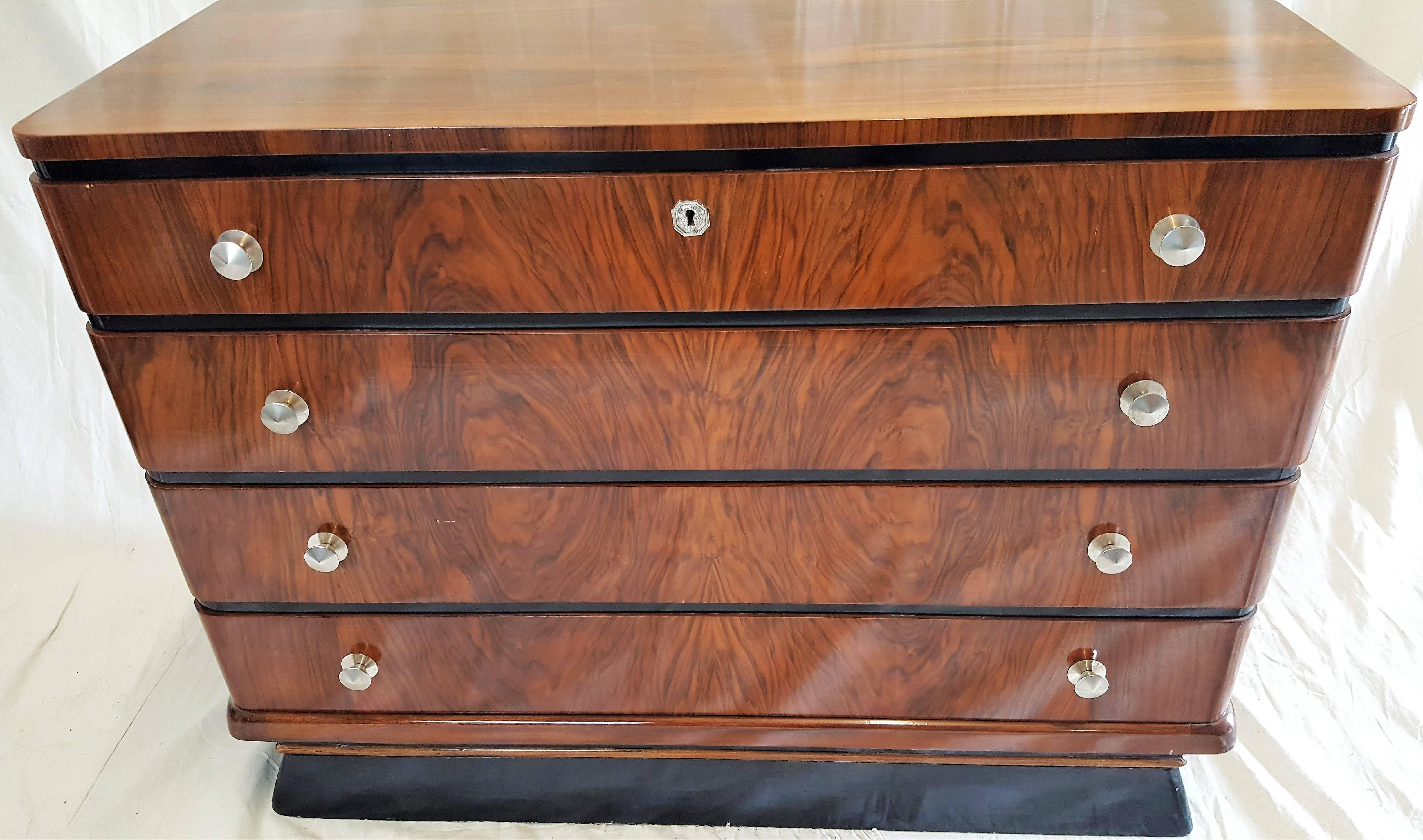 Four-drawer 1940s Art Deco Brazilian mahogany and chrome pulls with back base for strength. The technology and architecture of the deco period stands out in the curved corners, ebonized space between drawers and the base connecting to the floor.