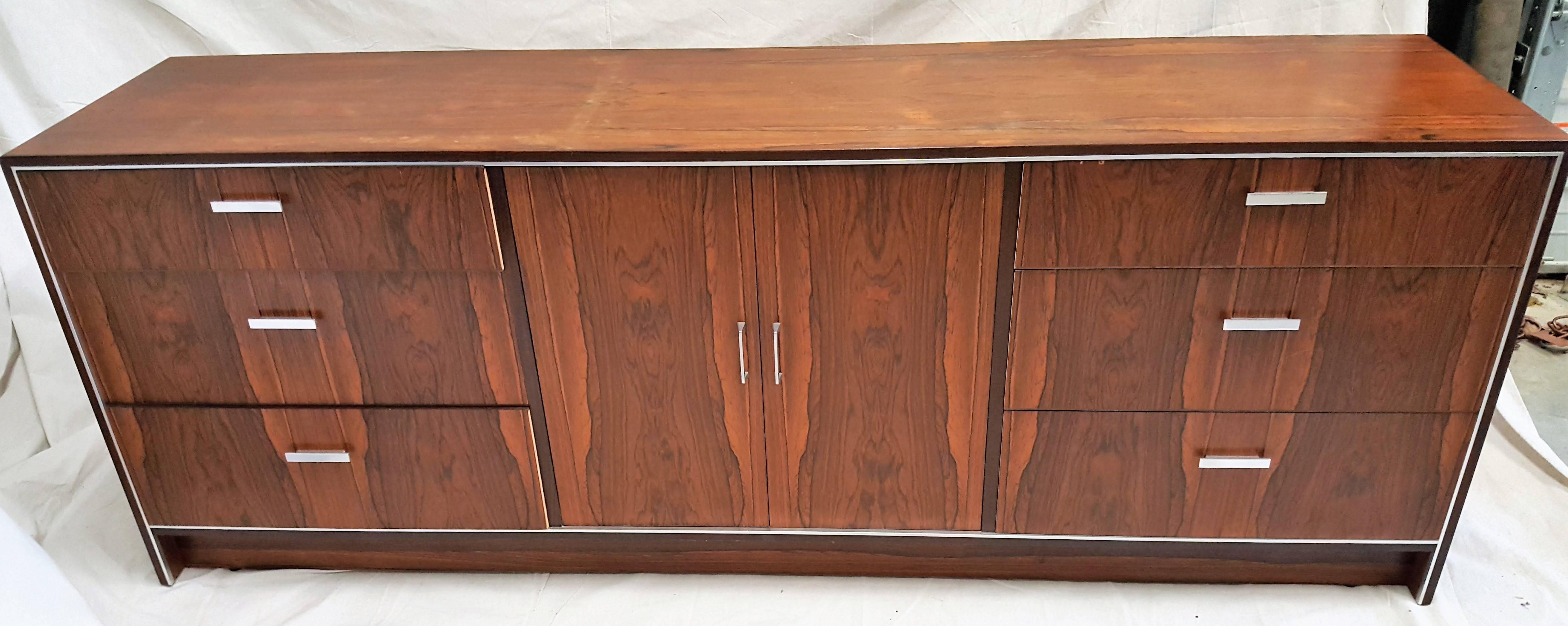 Beautiful rosewood Mid-Century dresser manufactured by Falster in Denmark. Notice the grain of the wood matches above and below. This lovely piece, which may be used as a bedroom dresser or console, has six drawers and closed two-door center, which