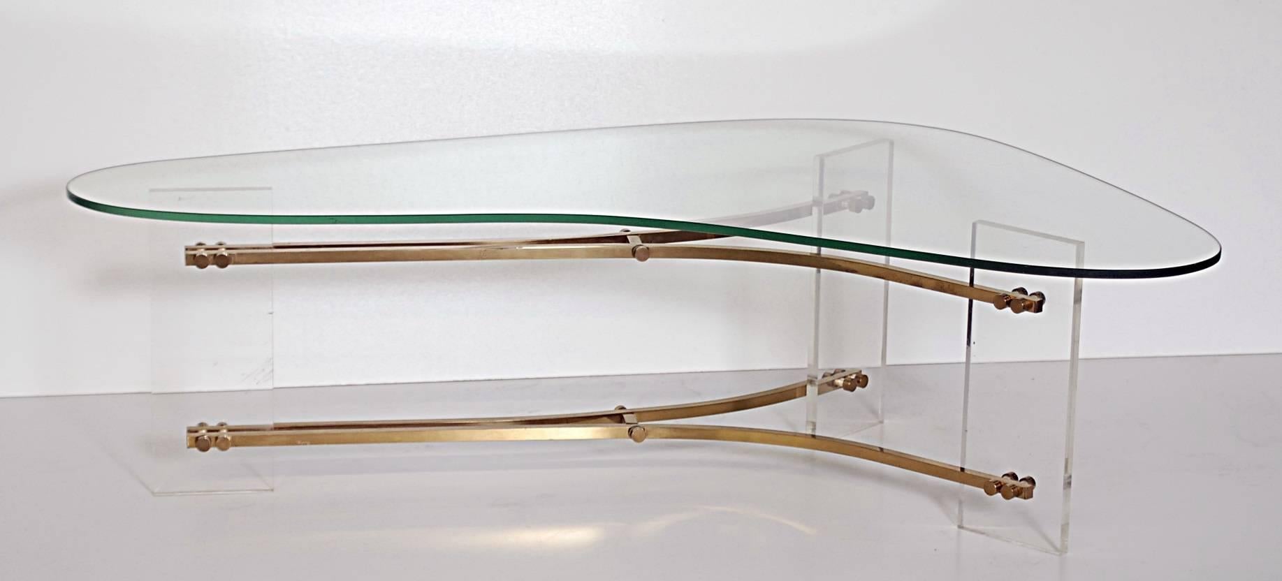 Kidney shaped glass top on Lucite supports attached with brass stretchers.