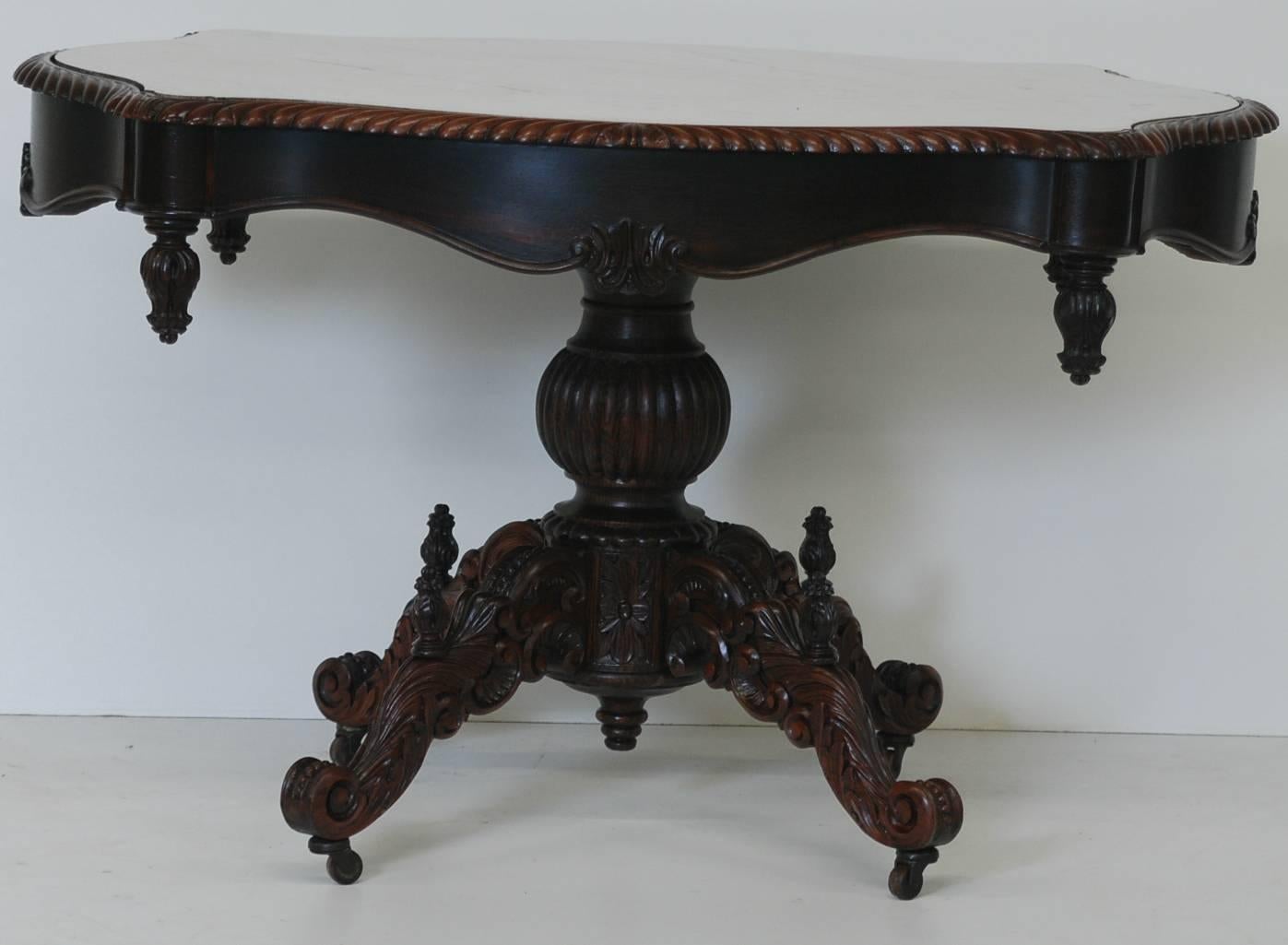 Carved mahogany marble turtle top center table on brass casters.