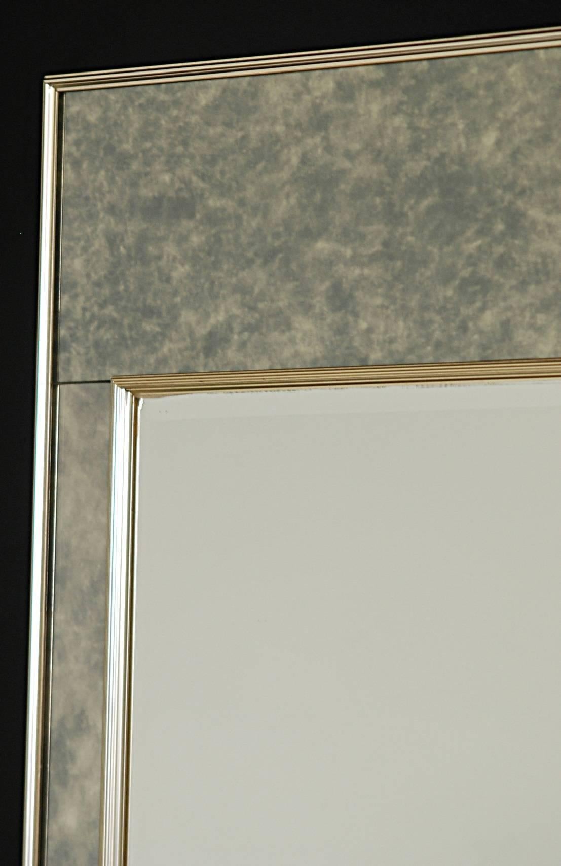 Antiqued mirror trim surrounding a beveled clear mirror insert in a brass frame.