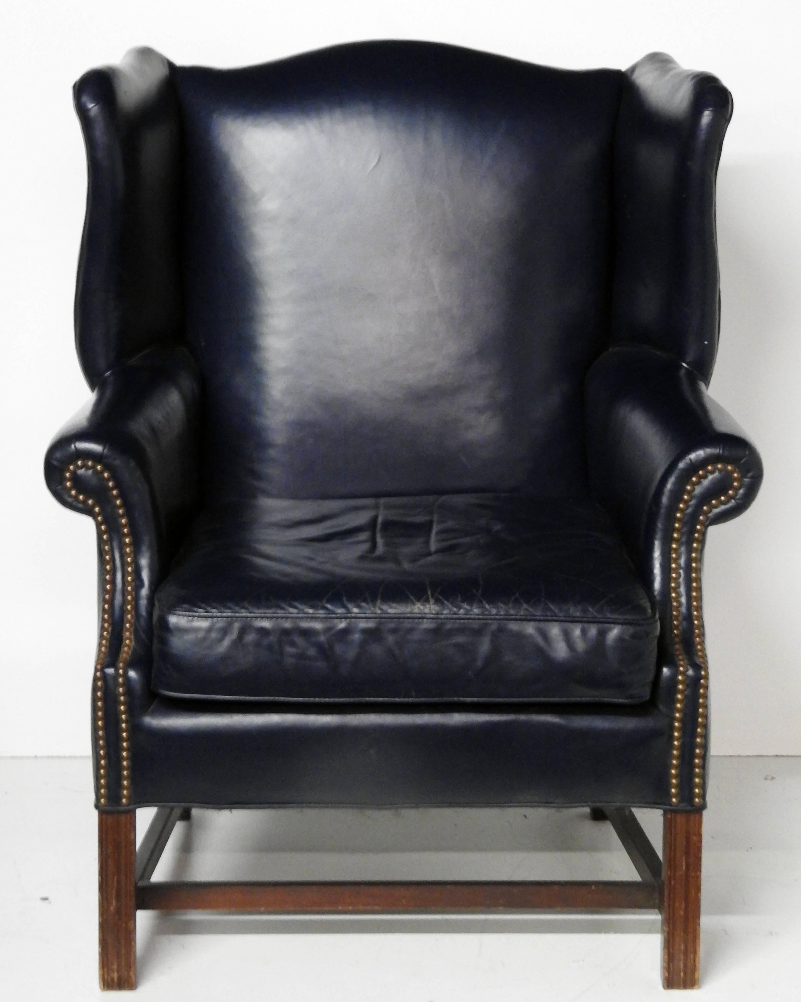 Georgian style wing chair with distressed leather upholstery and nailhead trim by Leathercraft.
