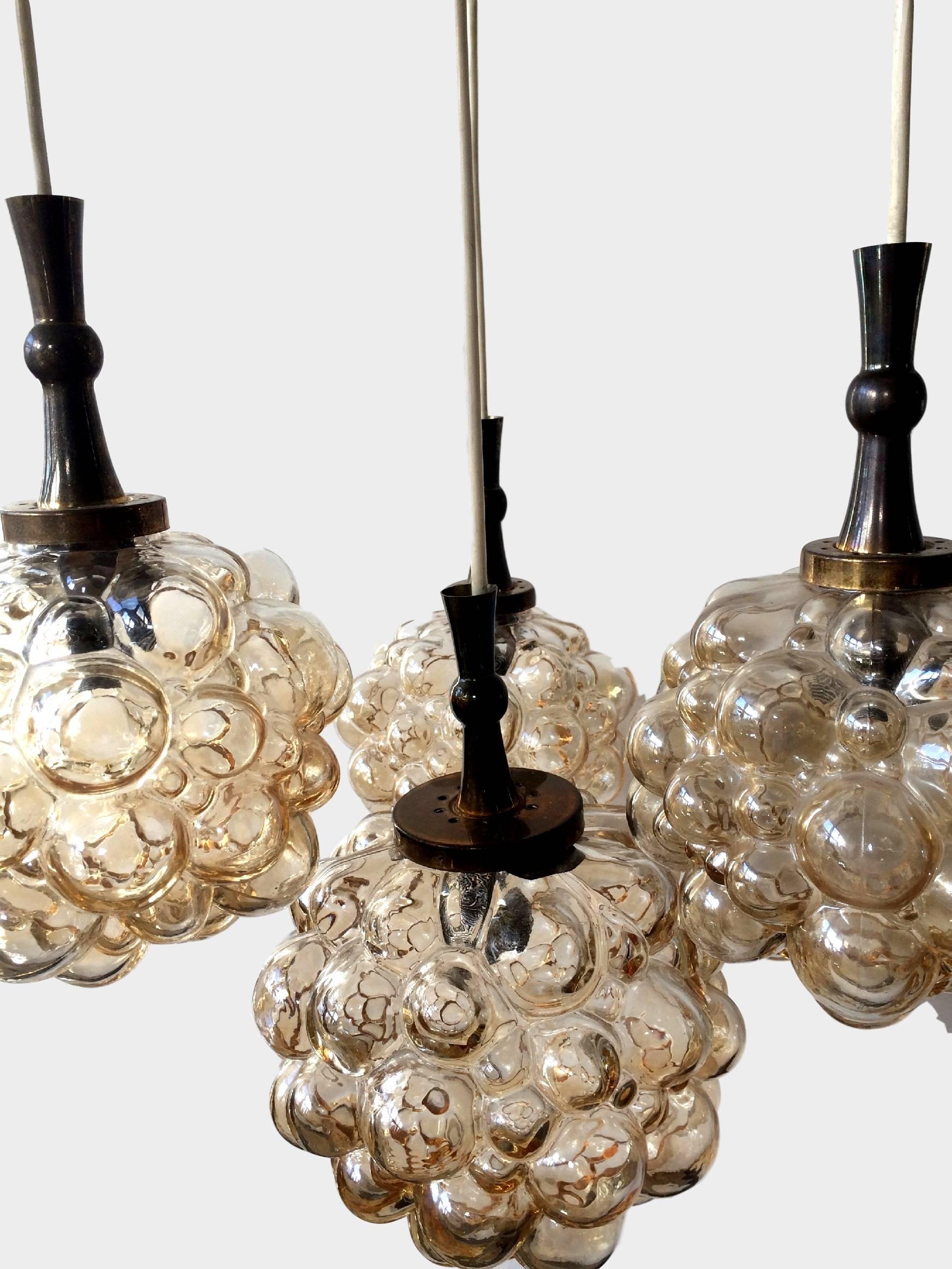 Impressive brass and amber toned glass bubble globe, four pendants chandelier

Thick amber colored bubbled glass globes in the style of Helena Tynell, by Limburg, Germany, circa 1960s.

Larger central pendant measures 20 cm tall, 22 cm wide,