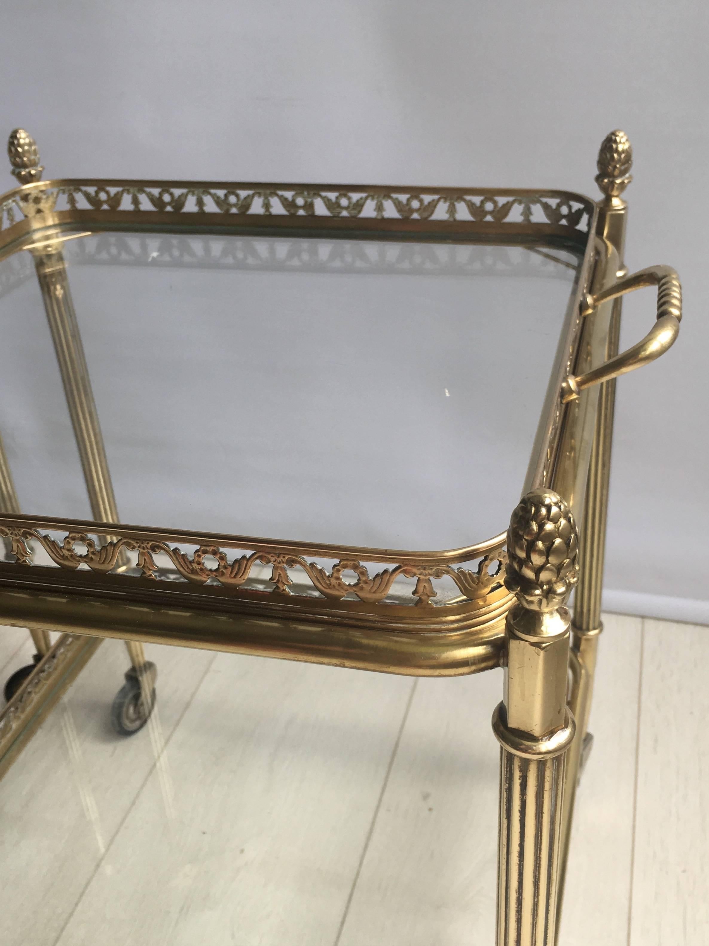 Perfect pair of brass side tables or trolleys from France, circa 1950

With decorative finials and lift off tray measuring 36cm square (44.5cm with handles)

Stands 46cm to glass, 51.5cm to finial.