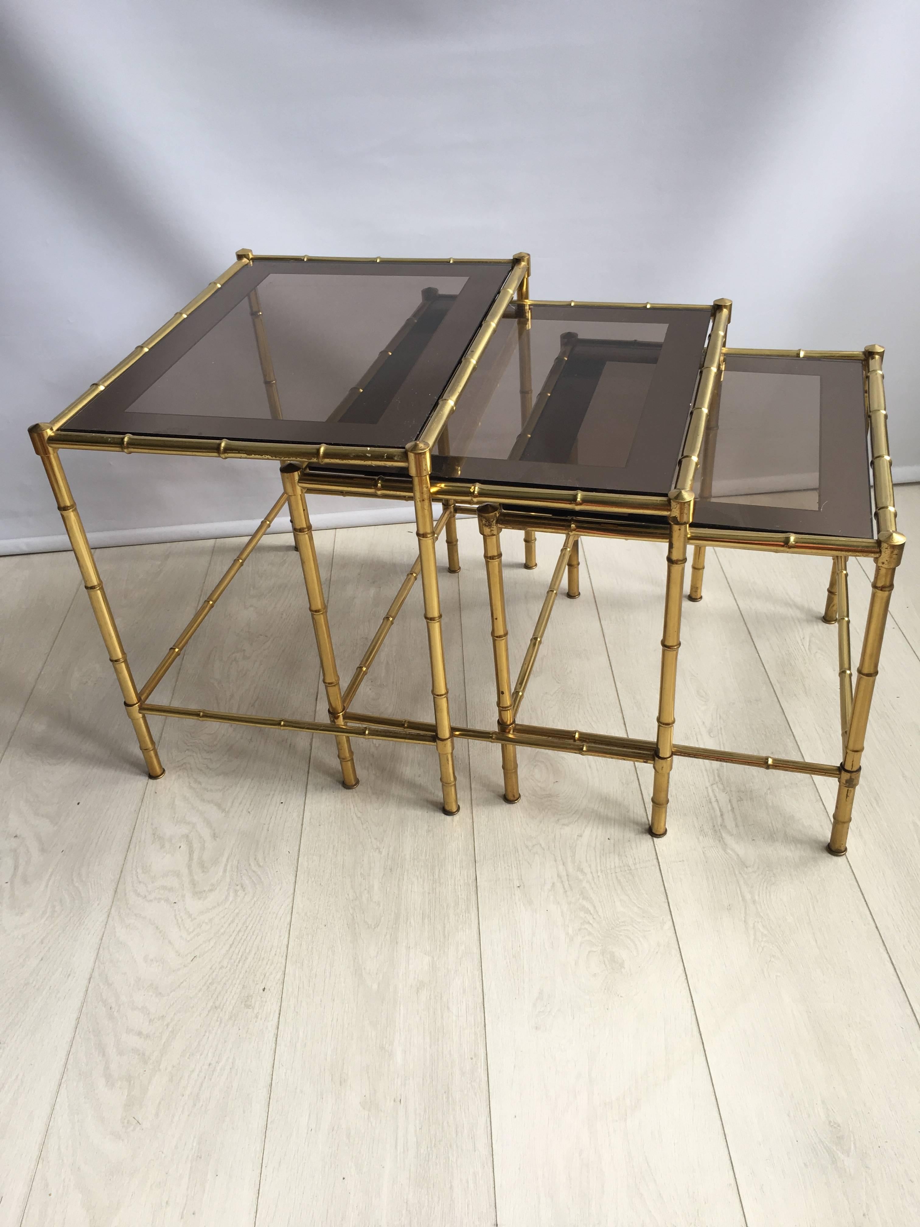 Great looking and extremely useful nest of tables from France, circa 1950.

Smoked glass top with lacquered brass frame.

Top table measures 52cm wide, 39cm deep and stands 46.5cm tall.
