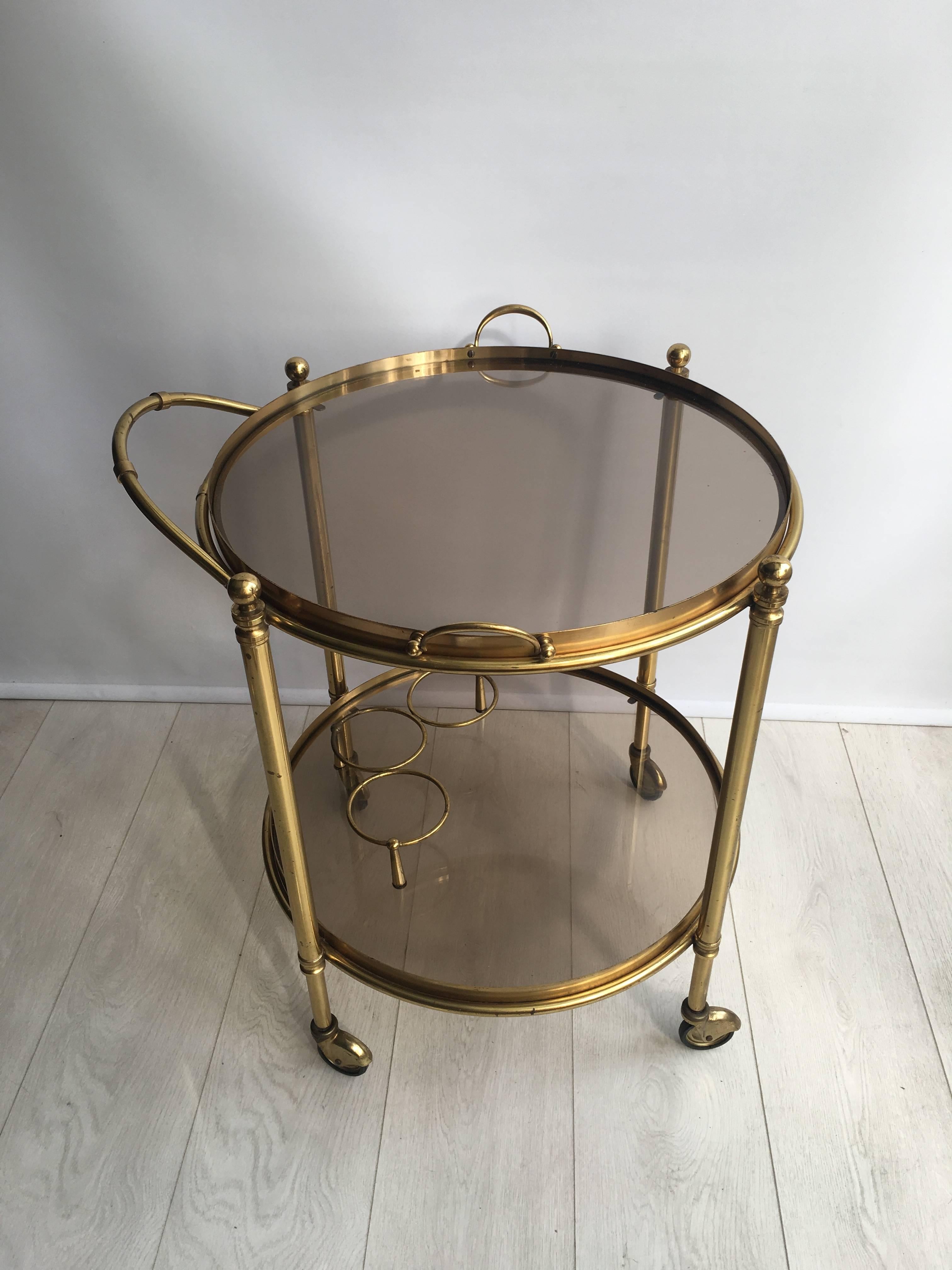 Great looking vintage drinks trolley, circa 1950.

Lacquered brass frame with aged patina (can be polished back if required), smoked glass shelves.

Lift off top tray and bottle holder to lower tier.

Top tray measures 50 cm across, 58.5 cm
