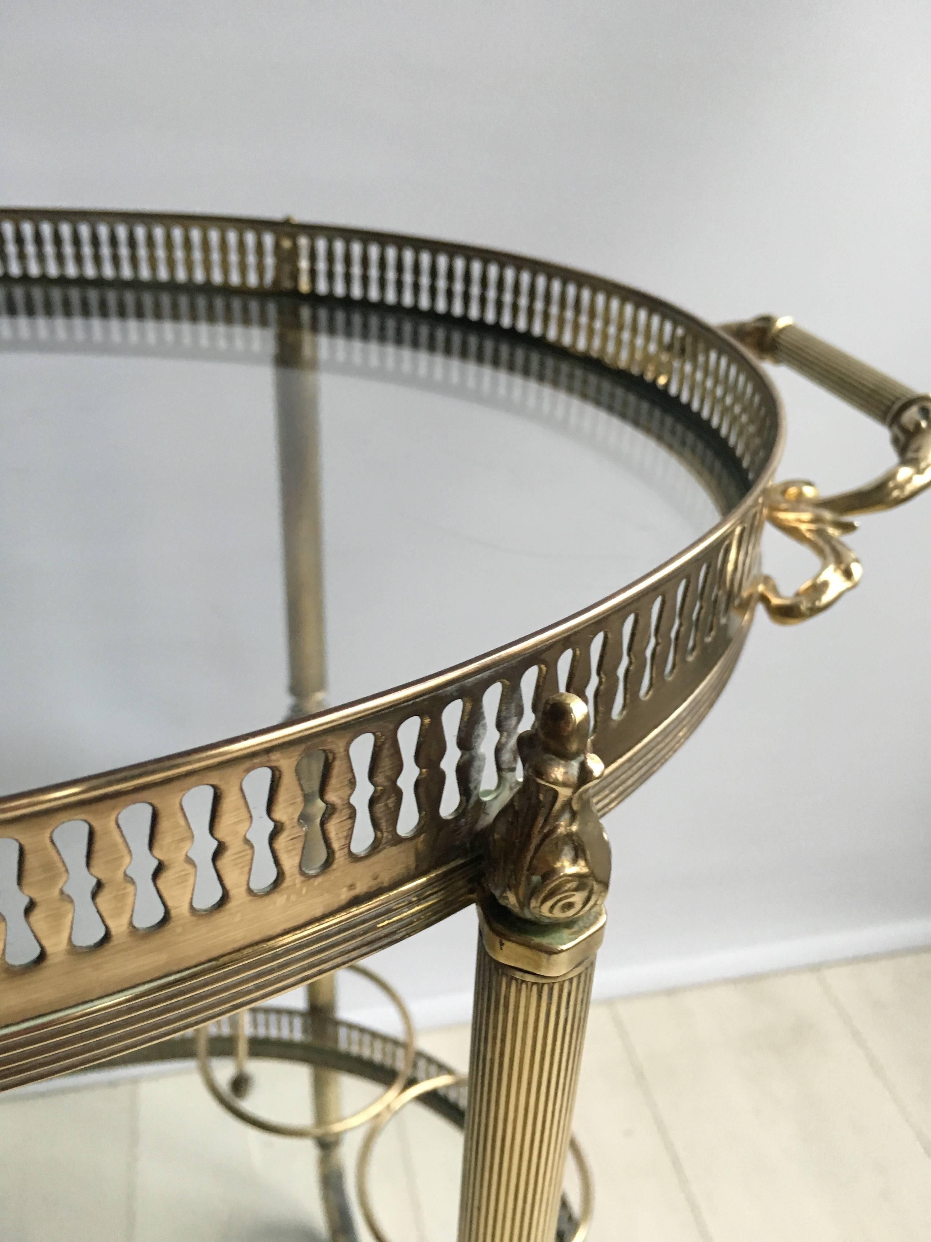 Beautiful oval drinks trolley with polished brass frame from France, circa 1950

Decorative finials and handle with bottle holder to lower tier

Top tray measures 53cm wide, 63cm with handles and 36cm deep. 
Stands 64cm to top glass, 66.5cm in