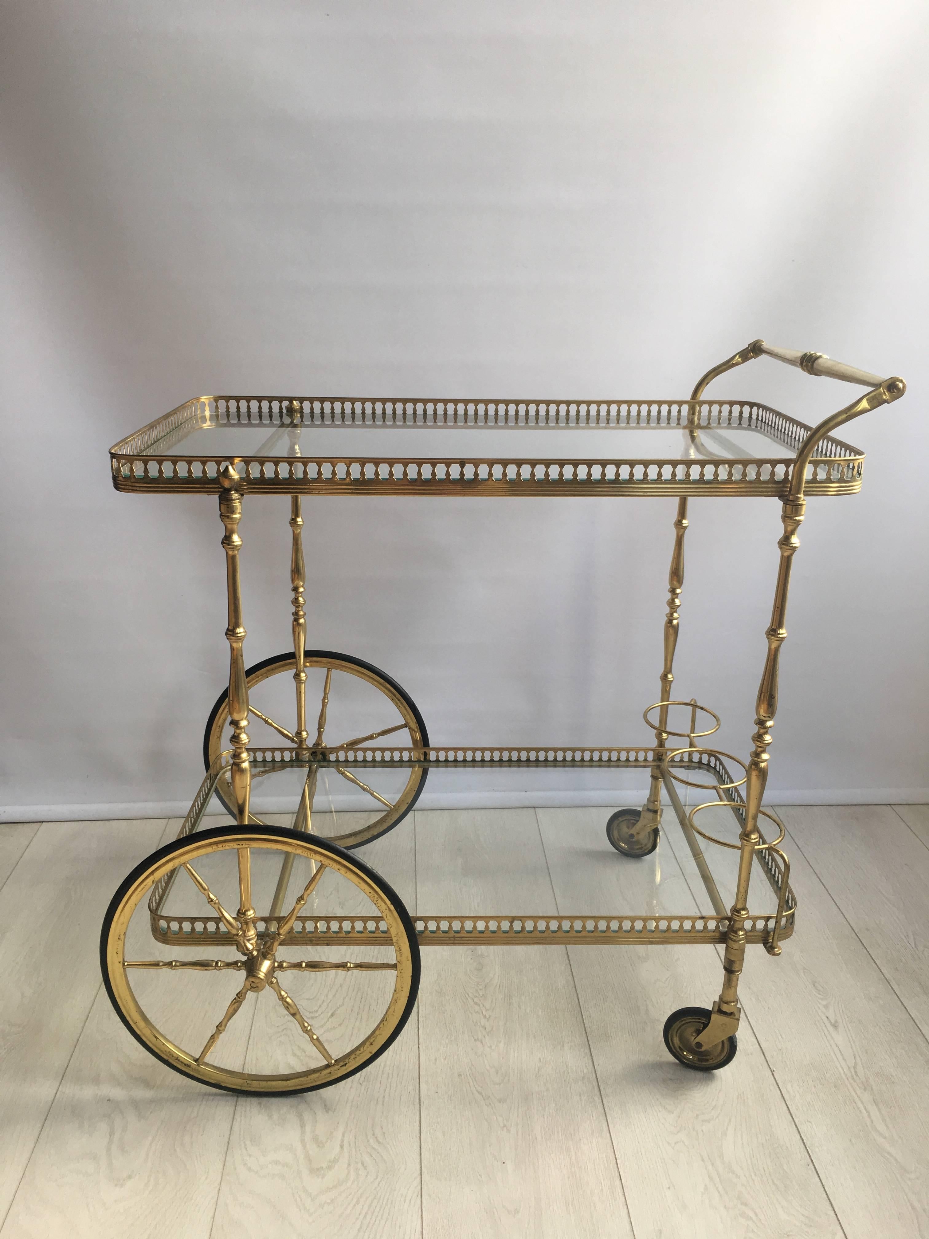 Classic vintage drinks trolley from France c1950

Lacquered brass frame with lovely aged patina

Bottle holder to lower tier

Top tray measures 70cm wide by 39.5cm deep and stands 66cm to the glass
Overall dims 73cm wide, 52cm deep and 75cm tall