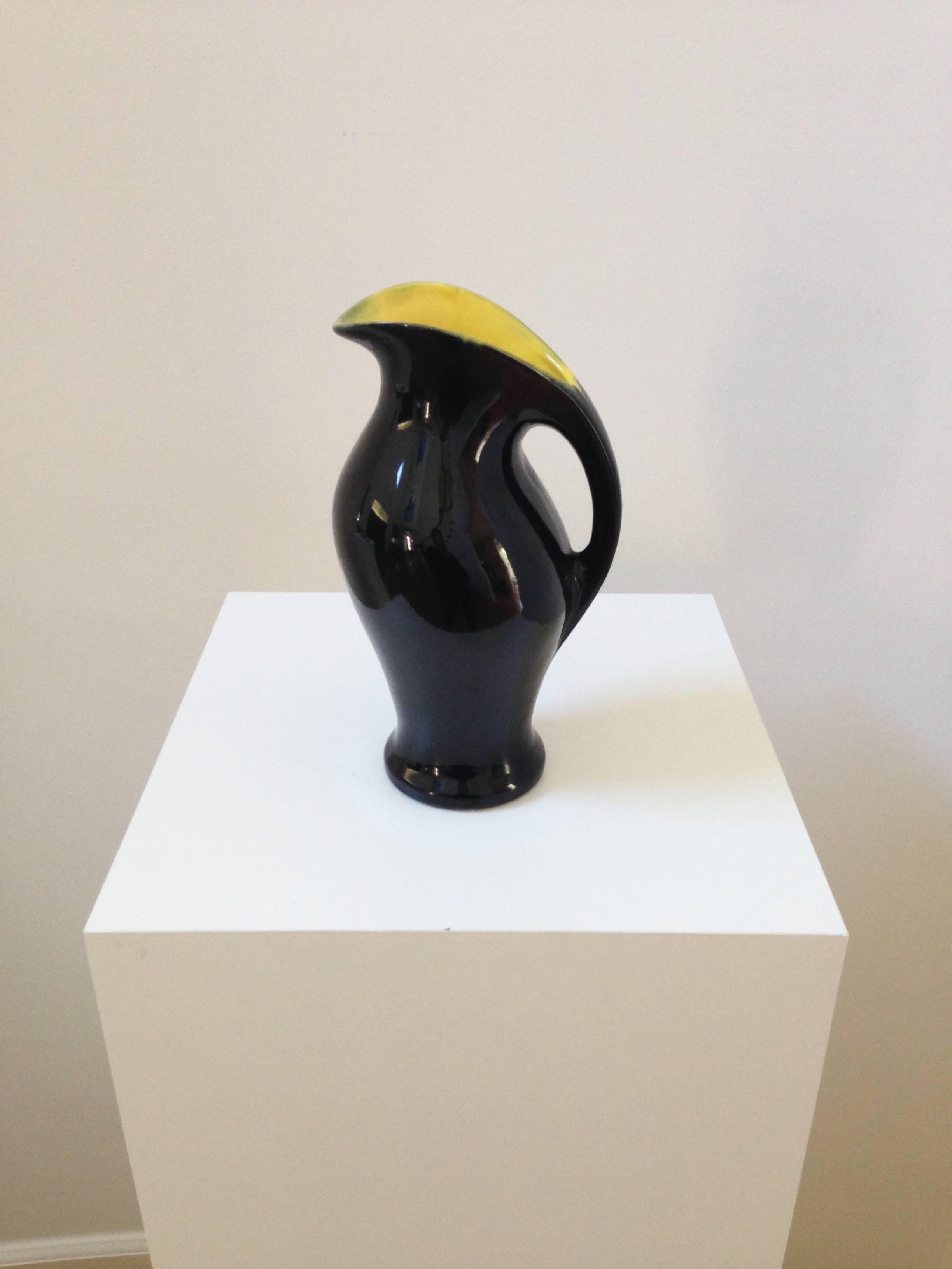 A fabulous modern ceramic pitcher in the style of Pol Chambost. The black exterior has a very nice glaze and sheen to it with a bright yellow interior. Sizable and quite practical for use, the pitcher's sculptural silhouette makes for a very