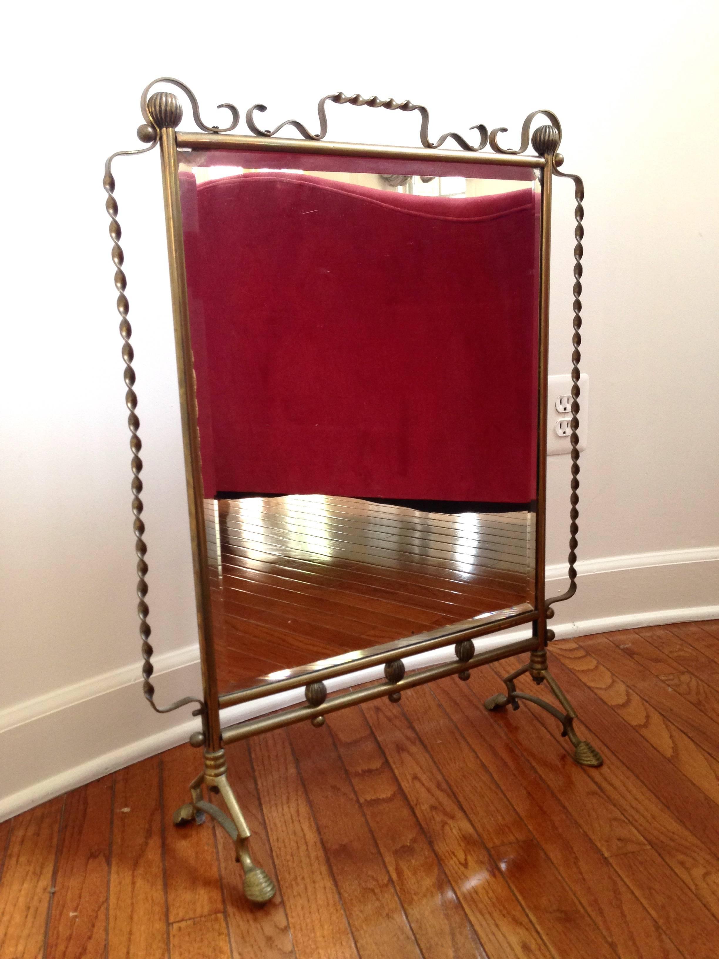 A very rare and stylish French fire screen very much in the style of Raymond Subes or Gilbert Poillerat. The mirrored front has beveled edges and the brass details including the legs are incredible.
