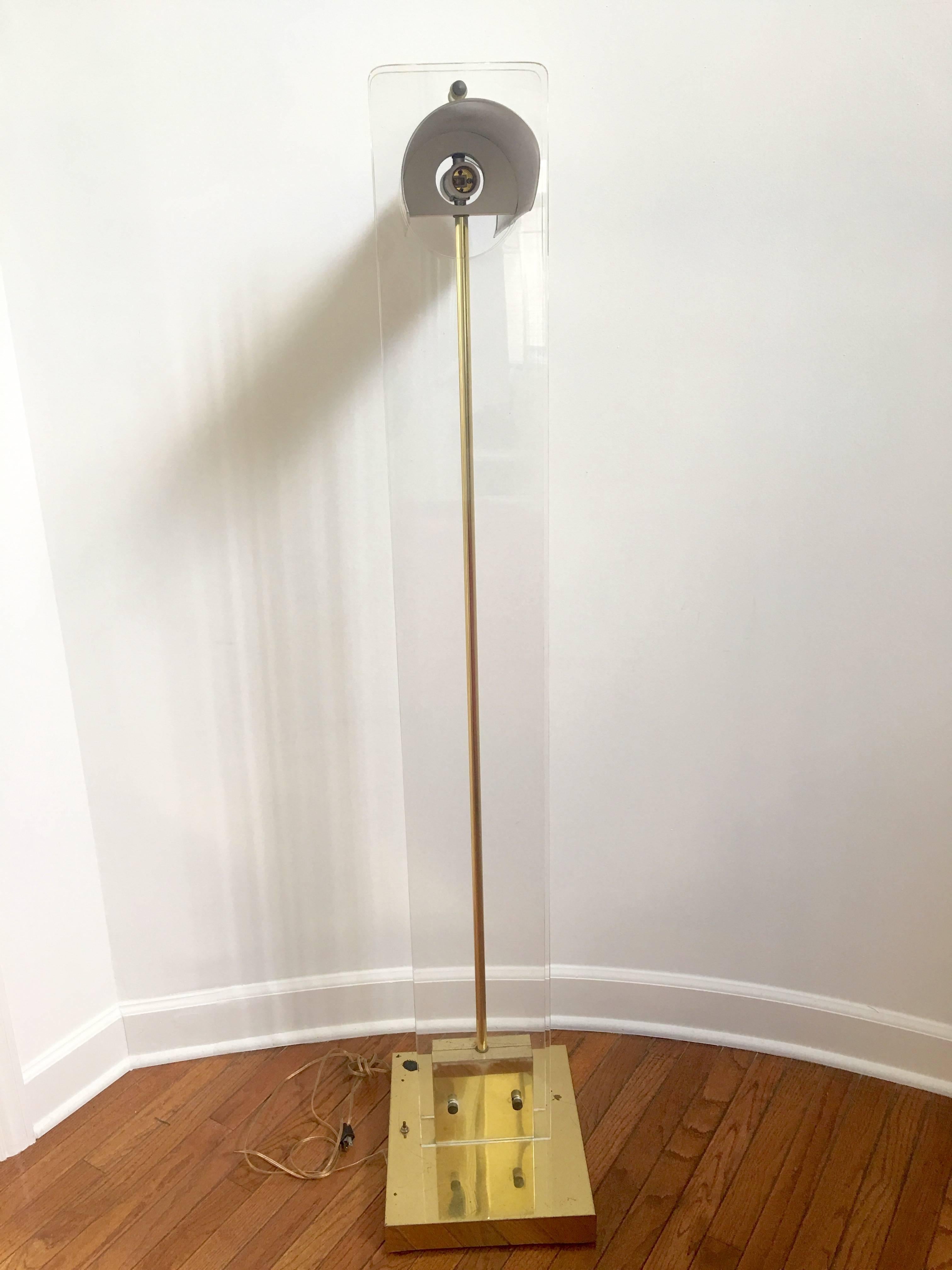 A fabulous and grand scale brass and Lucite floor lamp in the style of Pierre Cardin. The lamp has a heavy base and a pair of Lucite panels sandwiching a brass center stem. The shade is brass-plated and takes two regular bulbs.