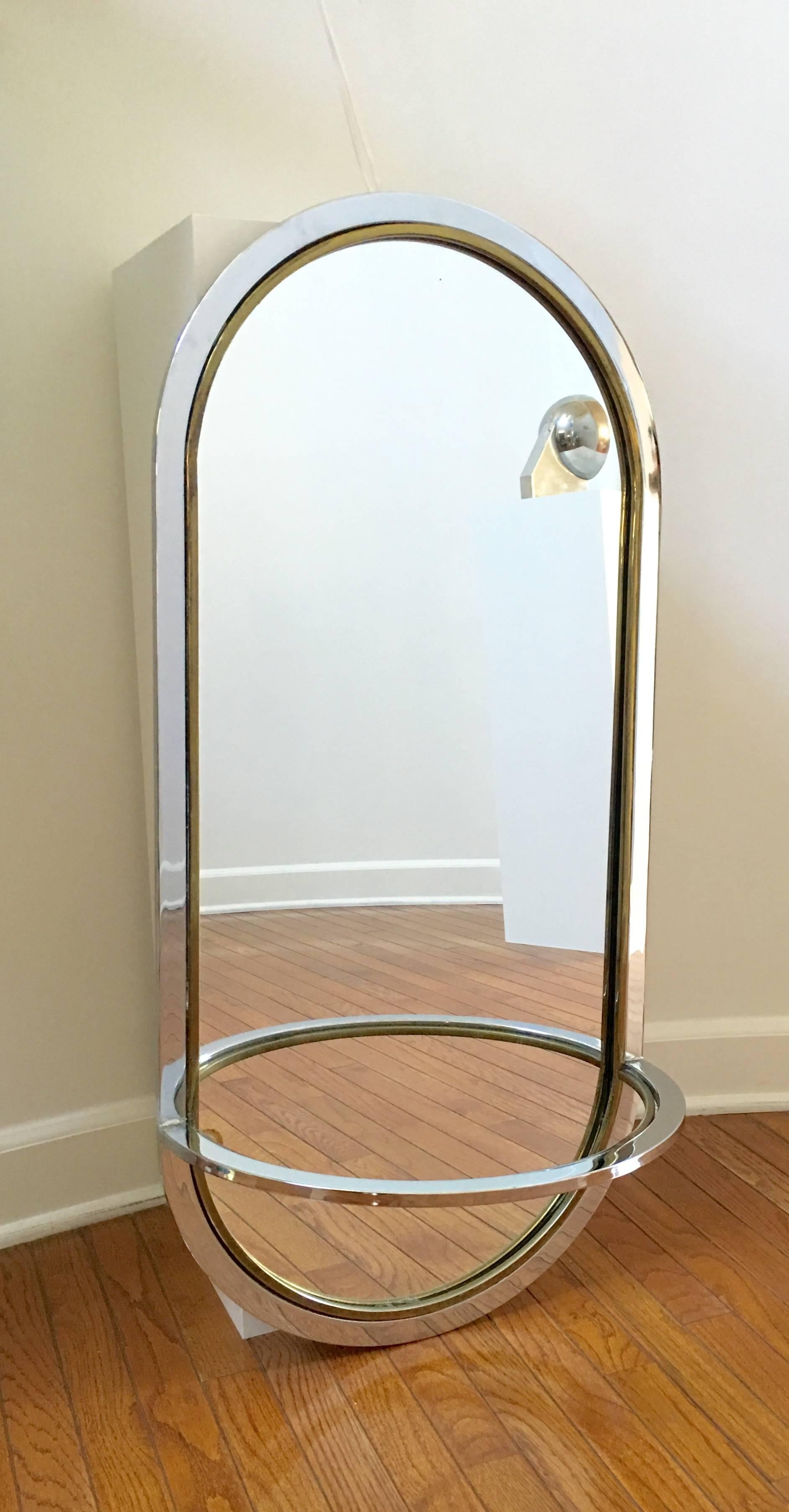 This 1970s style, oblong mirror has a chrome and brass frame with a shelf that has a clear Lucite inset. Wonderful presence and scale.