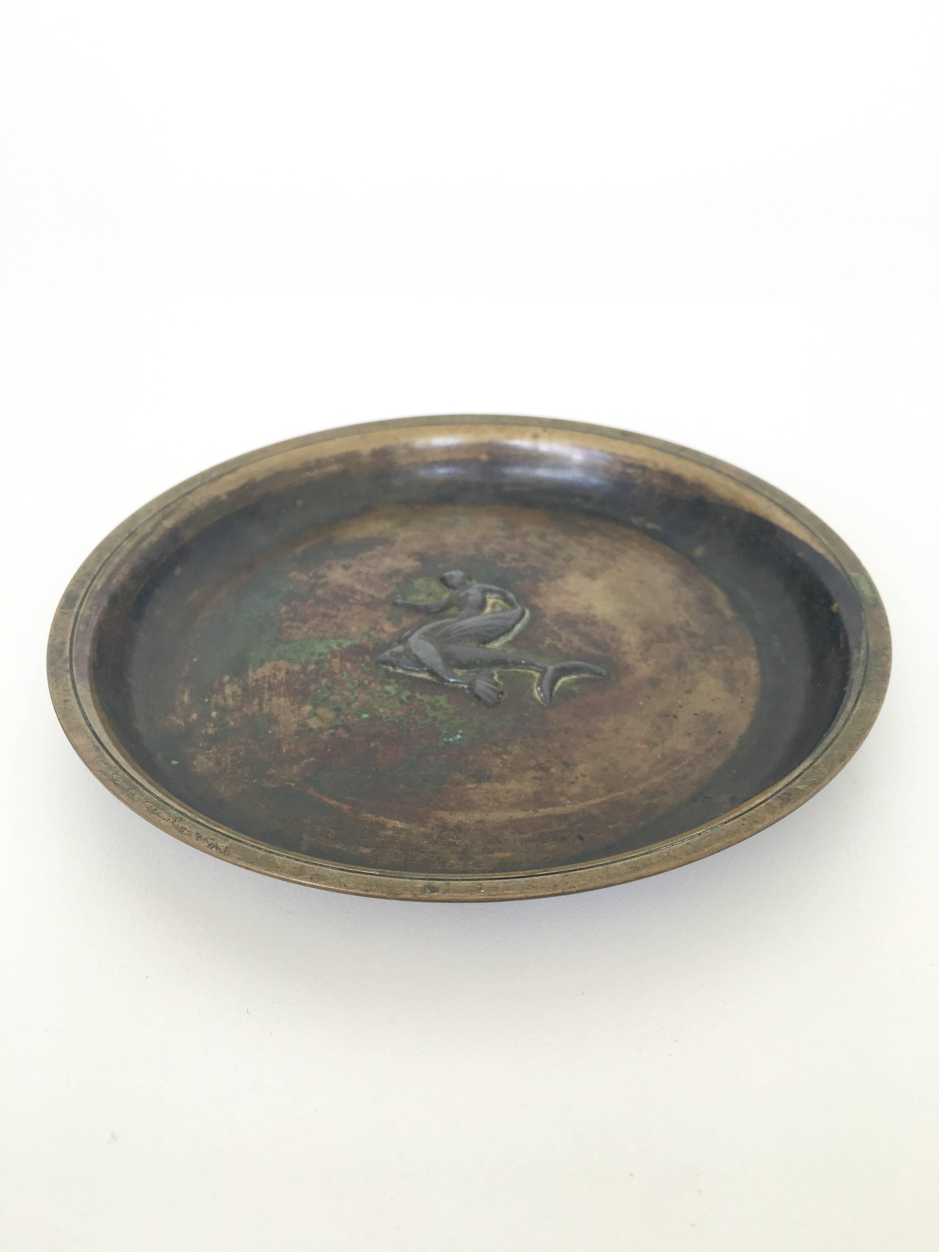 A lovely bronze dish with an embossed detail of a mermaid in the centre. The bronze has a wonderful dark patina and is signed at the bottom.