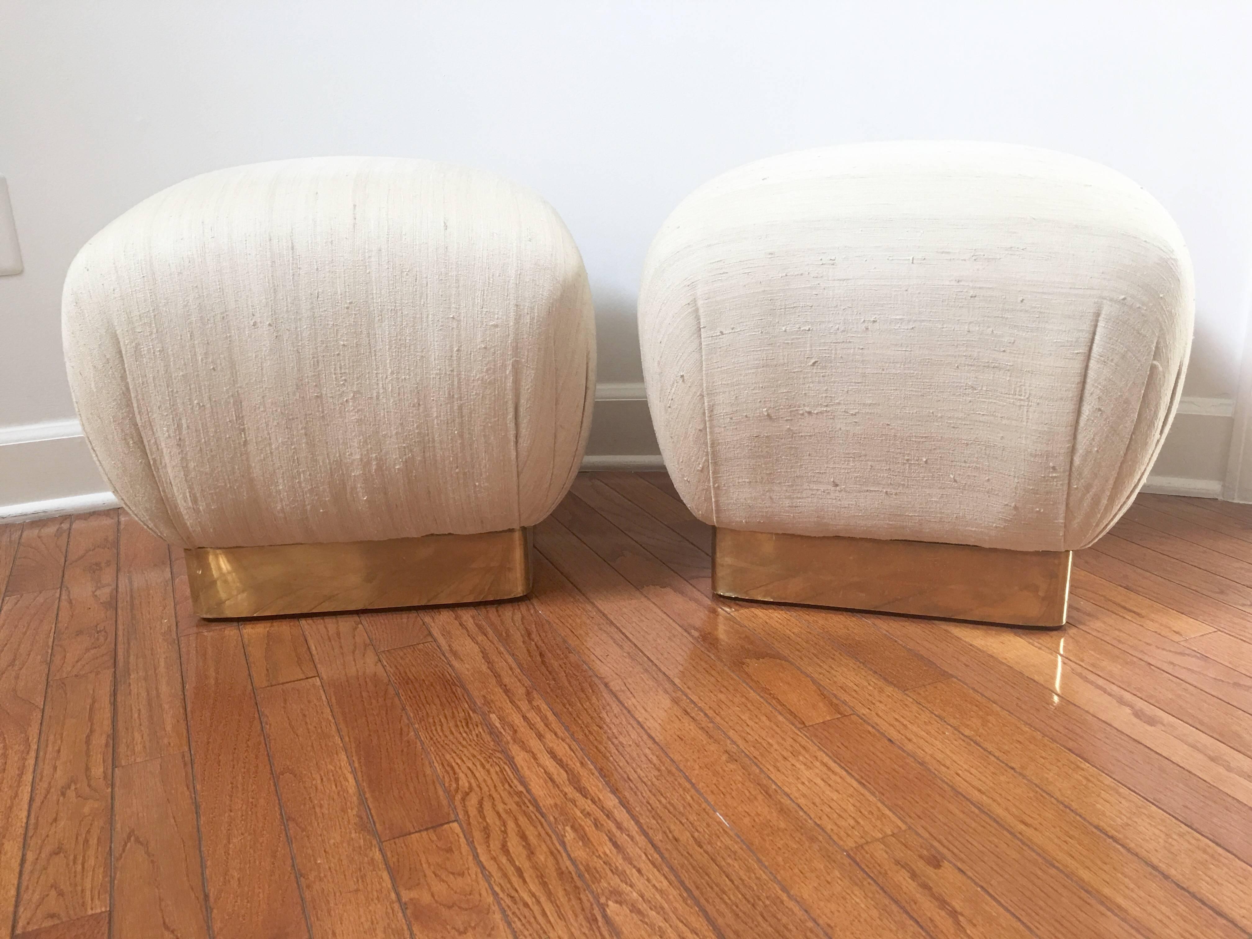 A stylish and comfortable pair of poufs by Marge Carson with brass plinths in the style of Karl Springer. Very much in vogue these poufs are one of the most versatile and timeless pieces found in the best interiors.
 