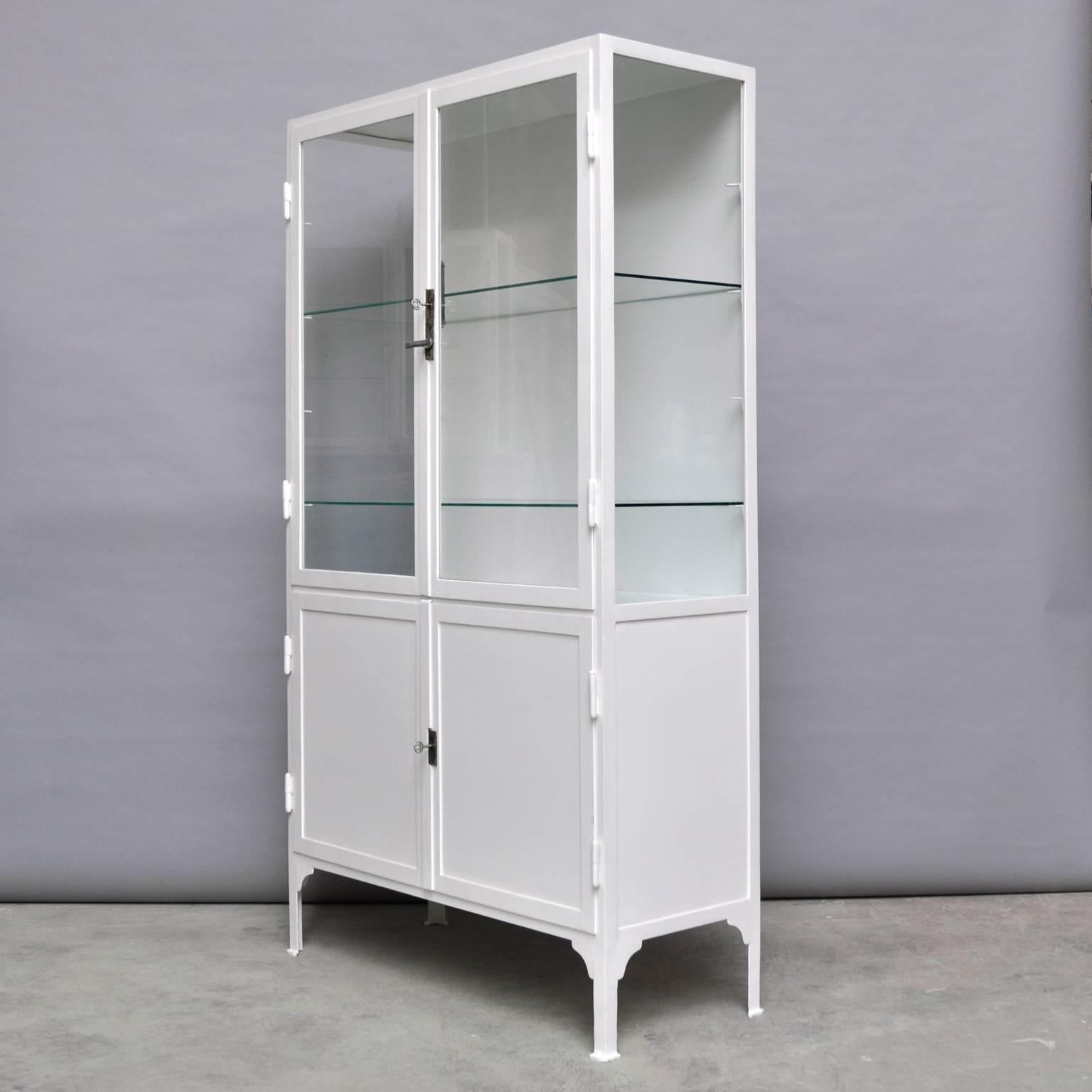 Vintage medical cabinet from the 1940s in excellent condition. The cabinet is produced in Hungary. In the top part, two glass shelves (four possible), in the lower part one steel shelf. Made of thick iron. The glass in the cabinet is the original