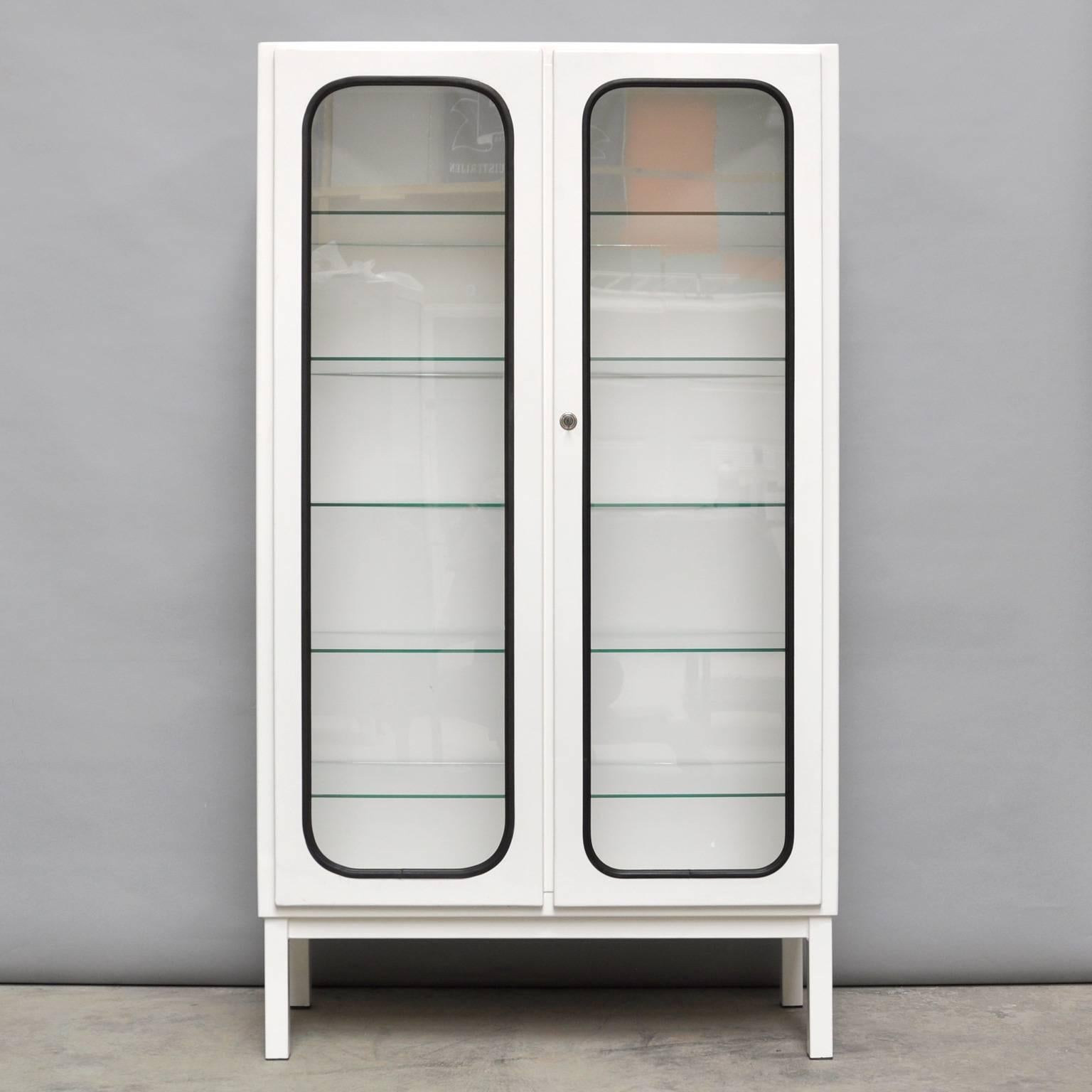 This medicine cabinet was designed in the 1960s and produced in the 1970s in Hungary. It is made of steel and glass and the glass is held by a black rubber strip. The cabinet comes with five adjustable glass shelves and a functioning lock. It is in