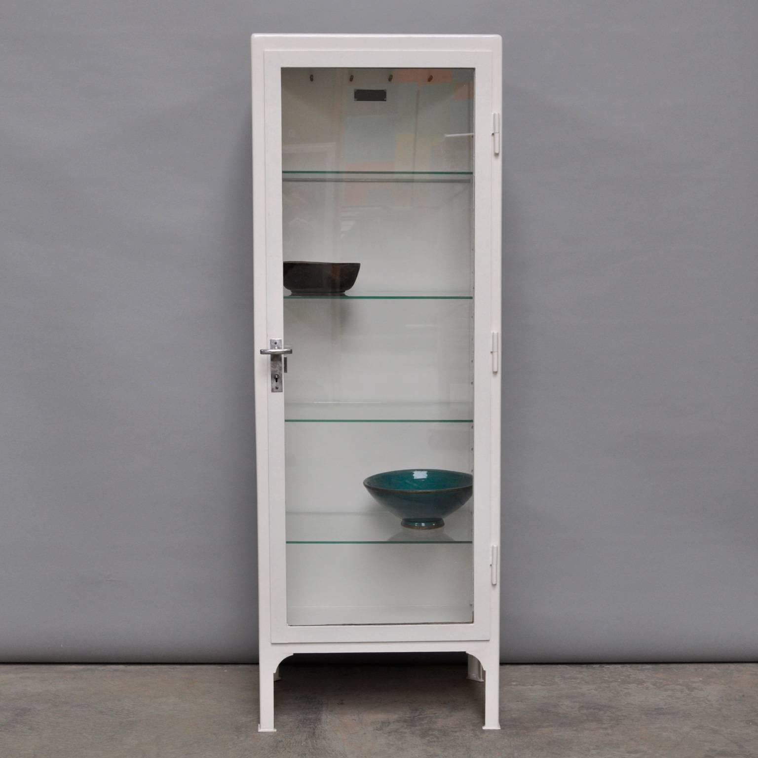 This vintage cabinet was produced in Poland during the 1950s. The cabinet is made of thick steel and comes with four glass shelves. The cabinet is restored and in good condition.