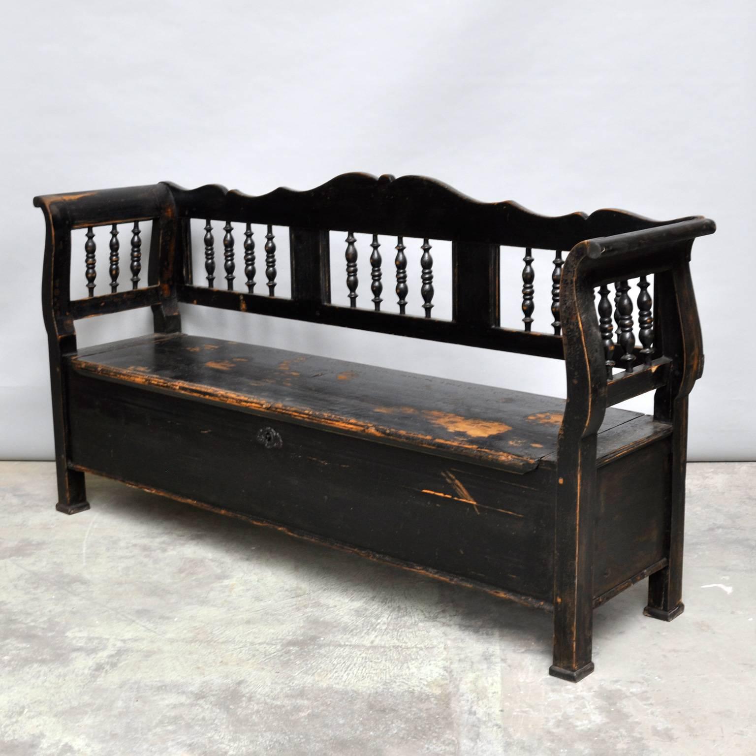 Gorgeous antique pine storage bench from Hungary painted black (original paint), circa 1900. The seat is a valve which opens to a five compartment storage space. The distressed painted finish adds character and charm to this storage bench. Where the