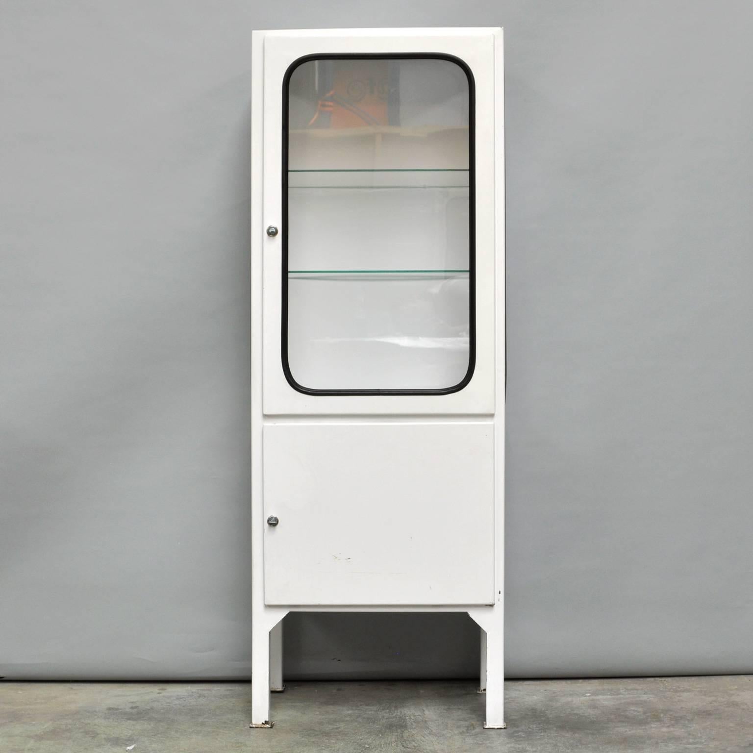 This medicine cabinet was designed in the 1960s and produced in the 1970s in Hungary. It is made of steel and glass and the glass is held by a black rubber strip. The cabinet comes with two adjustable glass shelves and functioning locks. It is in