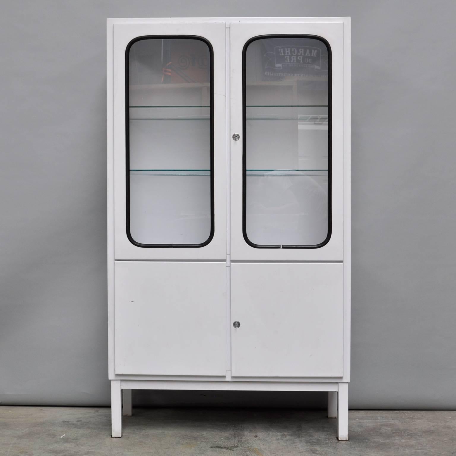 This medicine cabinet was designed in the 1960s and produced in the 1970s in Hungary. It is made of steel and glass and the glass is held by a black rubber strip. The cabinet comes with two adjustable glass shelves and functioning locks. It is in