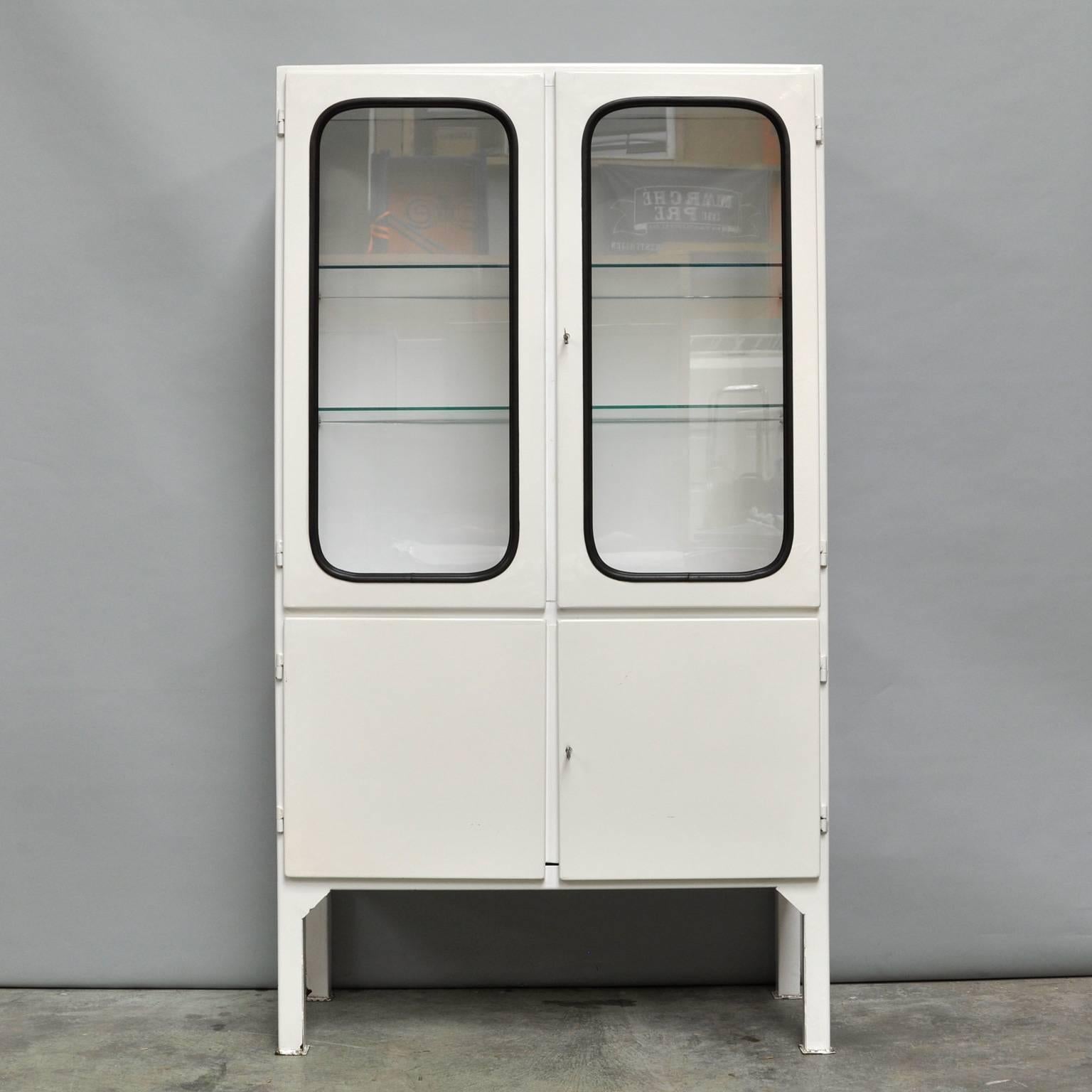 This medicine cabinet was designed in the 1960s and produced in the 1970s in Hungary. It is made from steel and glass and the glass is held by a black rubber strip. The cabinet comes with two adjustable glass shelves and functioning locks. It is in