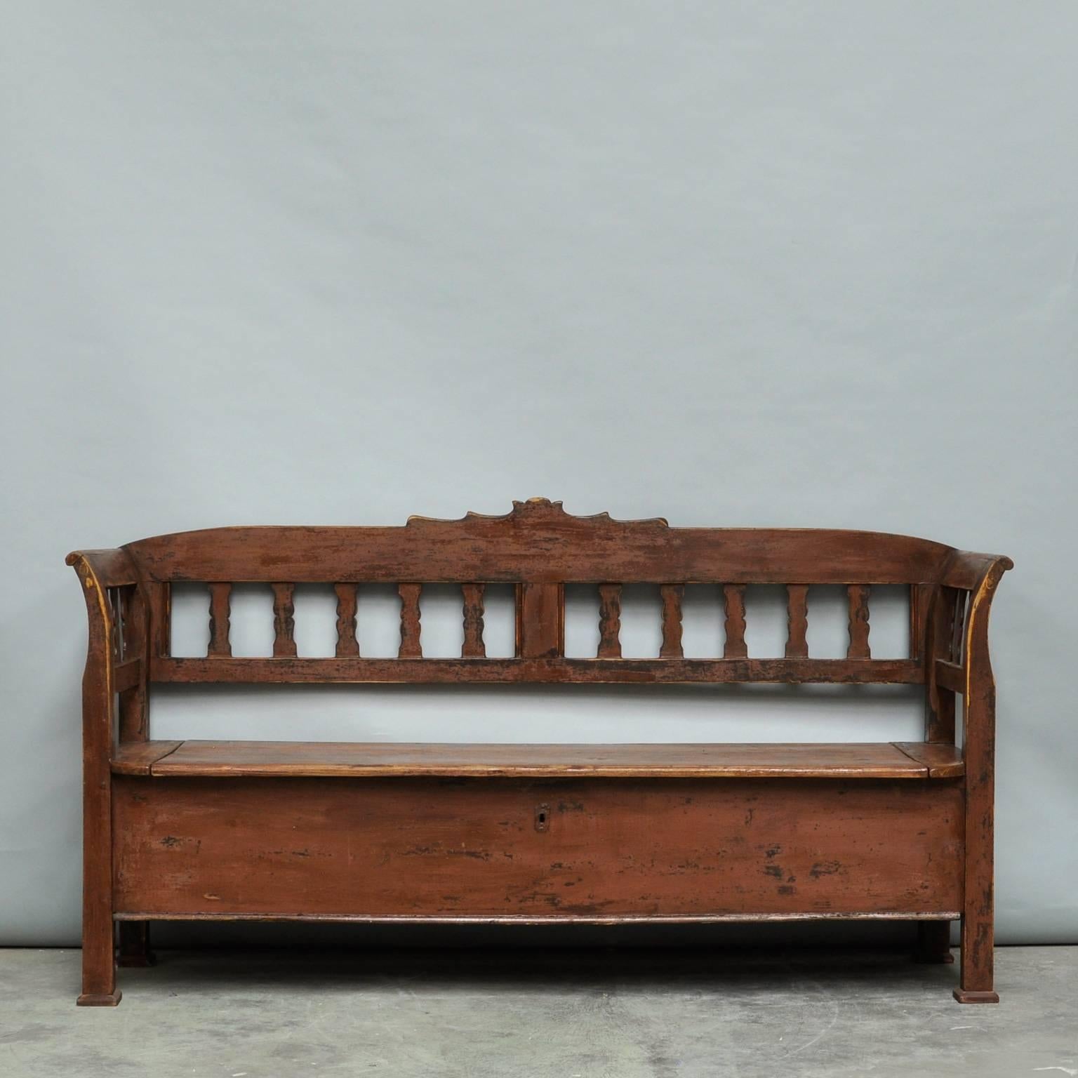This pine storage bench from Hungary was produced circa 1920 and retains its original paint. The seat opens upwards to reveal a three compartment storage space. The distressed painted finish where the paint is worn away allows the natural pine to