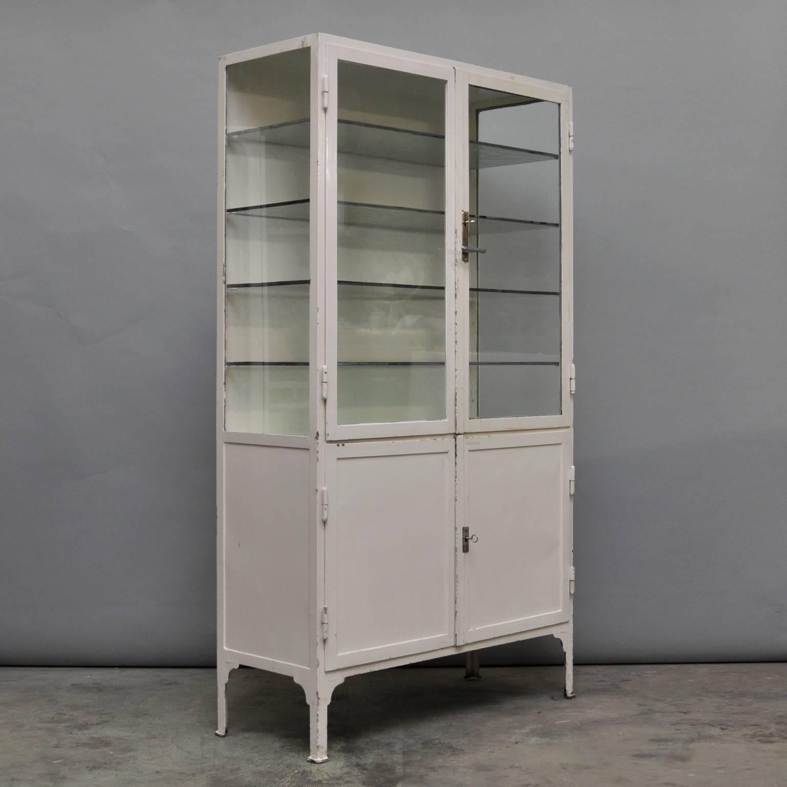 Medical cabinet, produced in de 1940s in Hungary. The cabinet is made of thick iron and antique glass. In the upper part the four original glass shelves. In the lower part one iron shelf. The cabinet has a very nice patina, some chips of paint