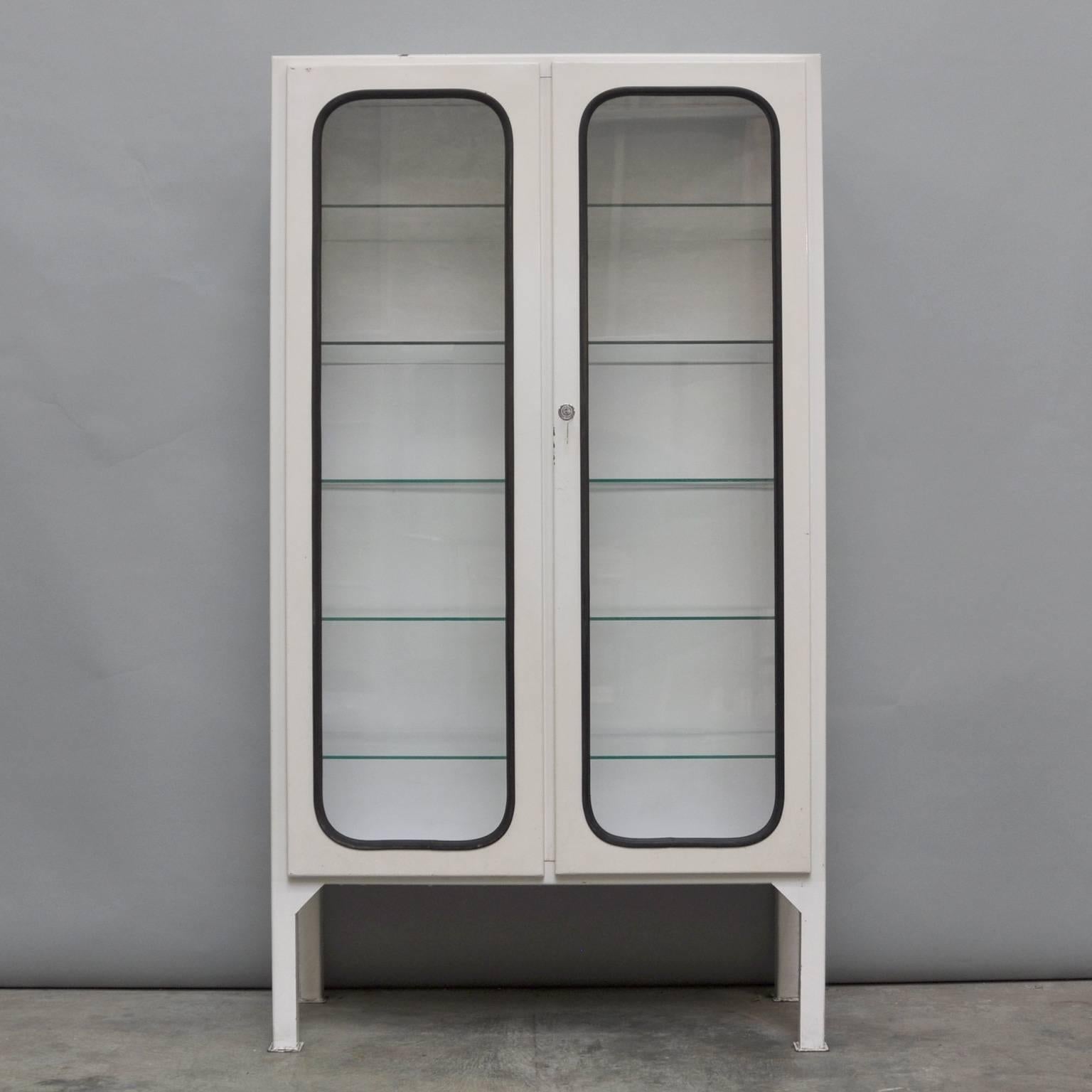This medicine cabinet was designed in the 1970s and was produced circa 1975 in Hungary. The piece is made from iron and antique glass, and the glass is held by a black rubber strip. The cabinet features five original adjustable glass shelves and a