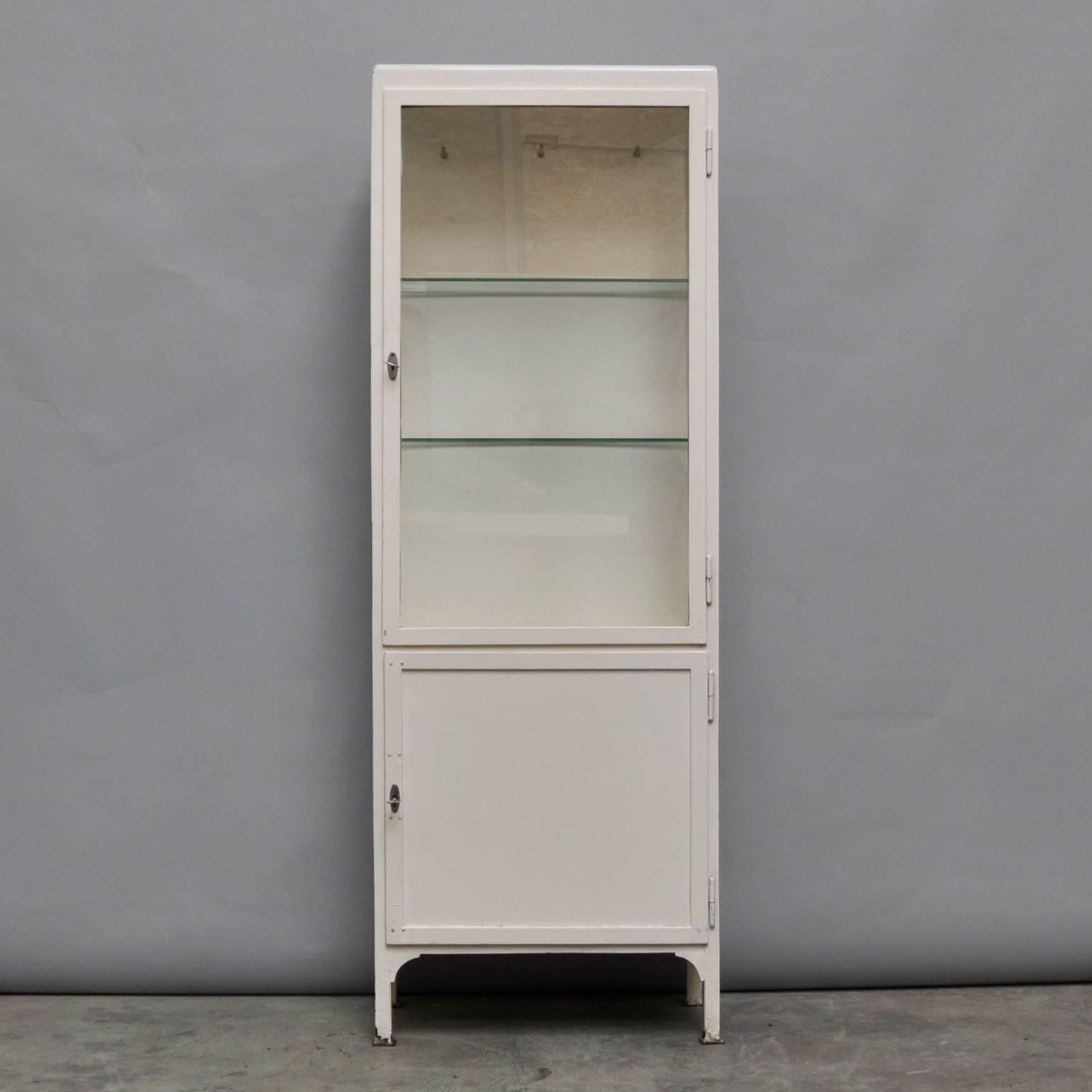 Charming hospital cabinet in good condition from the 1950s. The cabinet was produced in Poland and is made of iron and (antique) glass. In the upper part two adjustable glass shelves, and in the lower part two iron shelves.
  