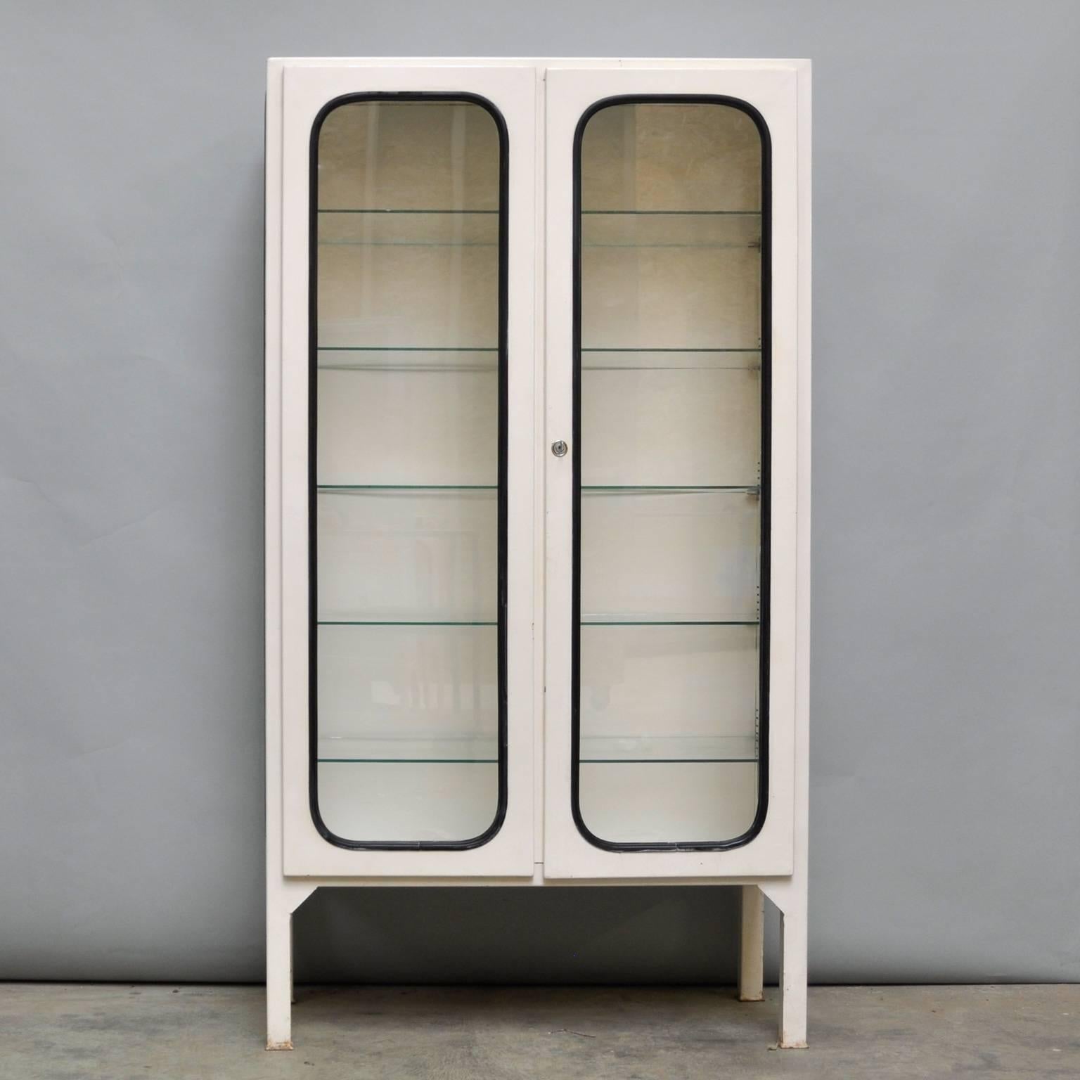 This medicine cabinet was designed in the 1970s and was produced, circa 1975 in Hungary. The piece is made from steel and antique glass, and the glass is held by a black rubber strip. The cabinet features five new adjustable glass shelves and a
