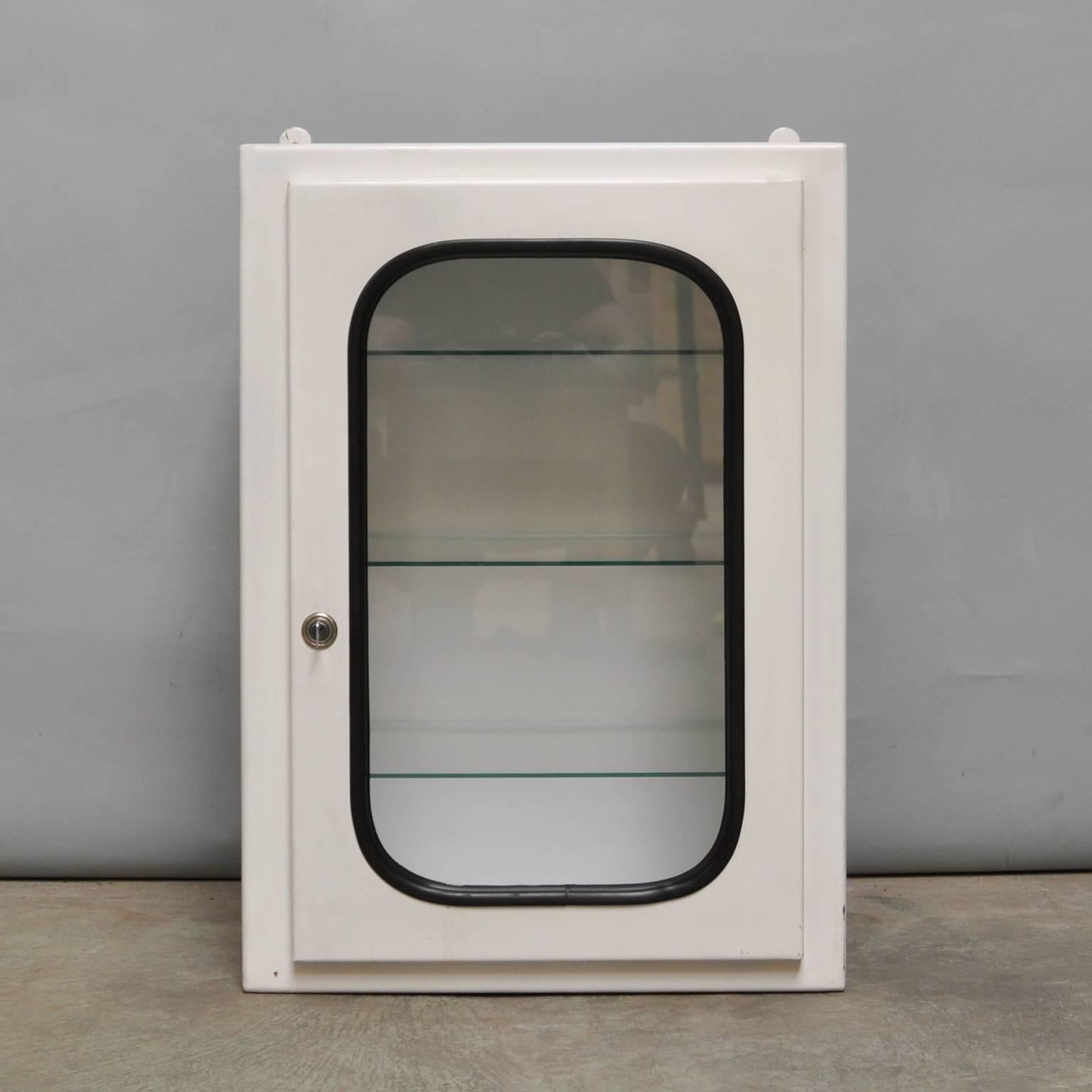 This medicine cabinet was designed in the 1970s and produced circa 1975 in Hungary. It is made of iron and glass. The glass is held by a black rubber strip. The cabinet comes with three adjustable glass shelves and a functioning lock.