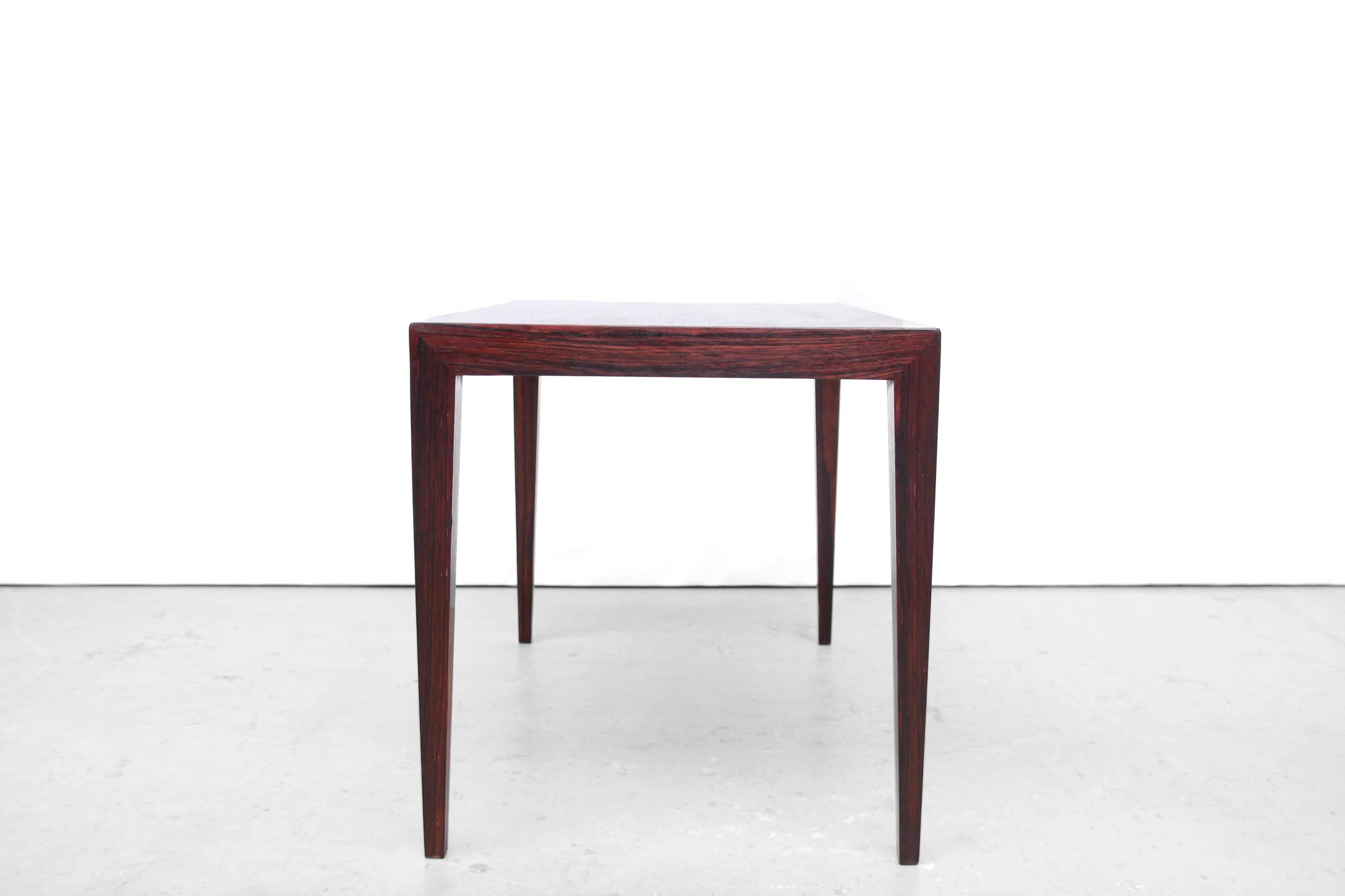 Very nice and subtle side table or small coffee table designed by Severin Hansen jr for Haslev Møbelfabrik from Denmark. Beautiful grained dark wood.
Look at the geometric connection of the legs to the tabletop. 
Severin Hansen is well-known by