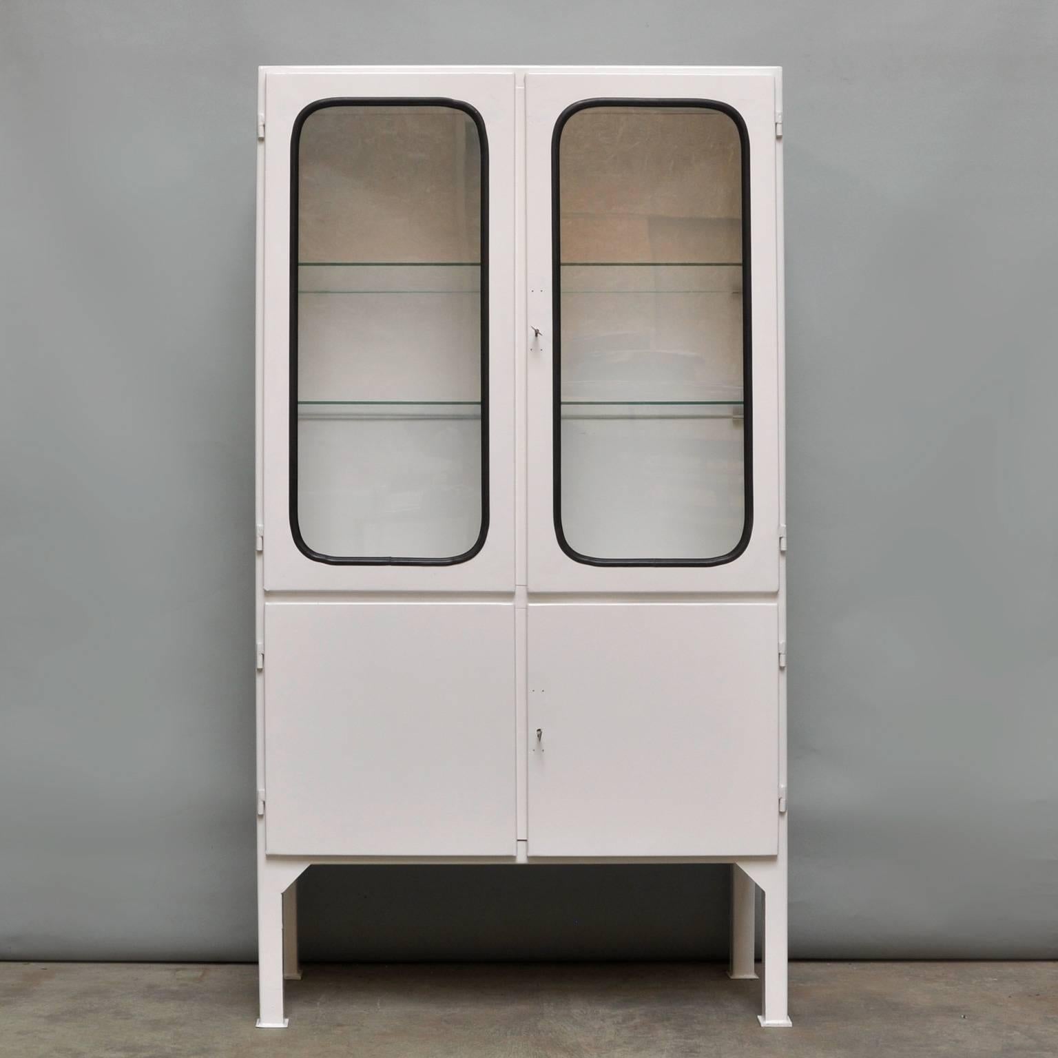 This medicine cabinet was designed in the 1970s and was produced circa 1975 in Hungary. It is made from iron and antique glass, and the glass is held by a black rubber strip. The cabinet features three (new) adjustable glass shelves and functioning