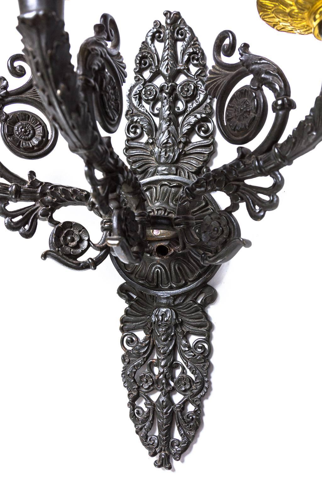 A pair of sconces with three arms and sockets to hold candles, France 1810-1820, Restauration period in cast iron and brass. On the reverse of the back plate a signature that is hard to be deciphered. The cast iron with fine scrolls, flowers and