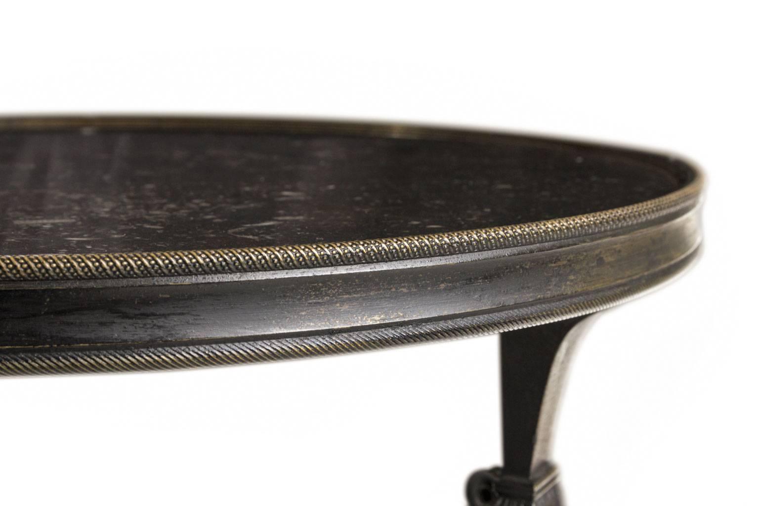 A classical round Gueridon with a base in blackened bronze and a top in marble Noir de Belgique.