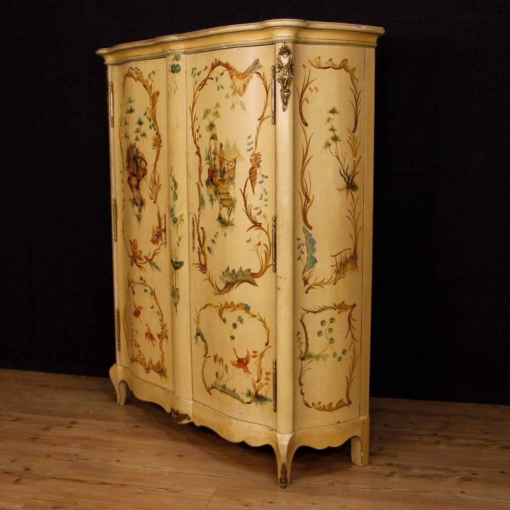 French wardrobe of the 20th century. Furniture in wood richly decorated with bronzes and chinoiserie painted ornaments. Two-doors armoire of excellent capacity and service. Interior complete with several shelves, of which two with drawers. Wardrobe