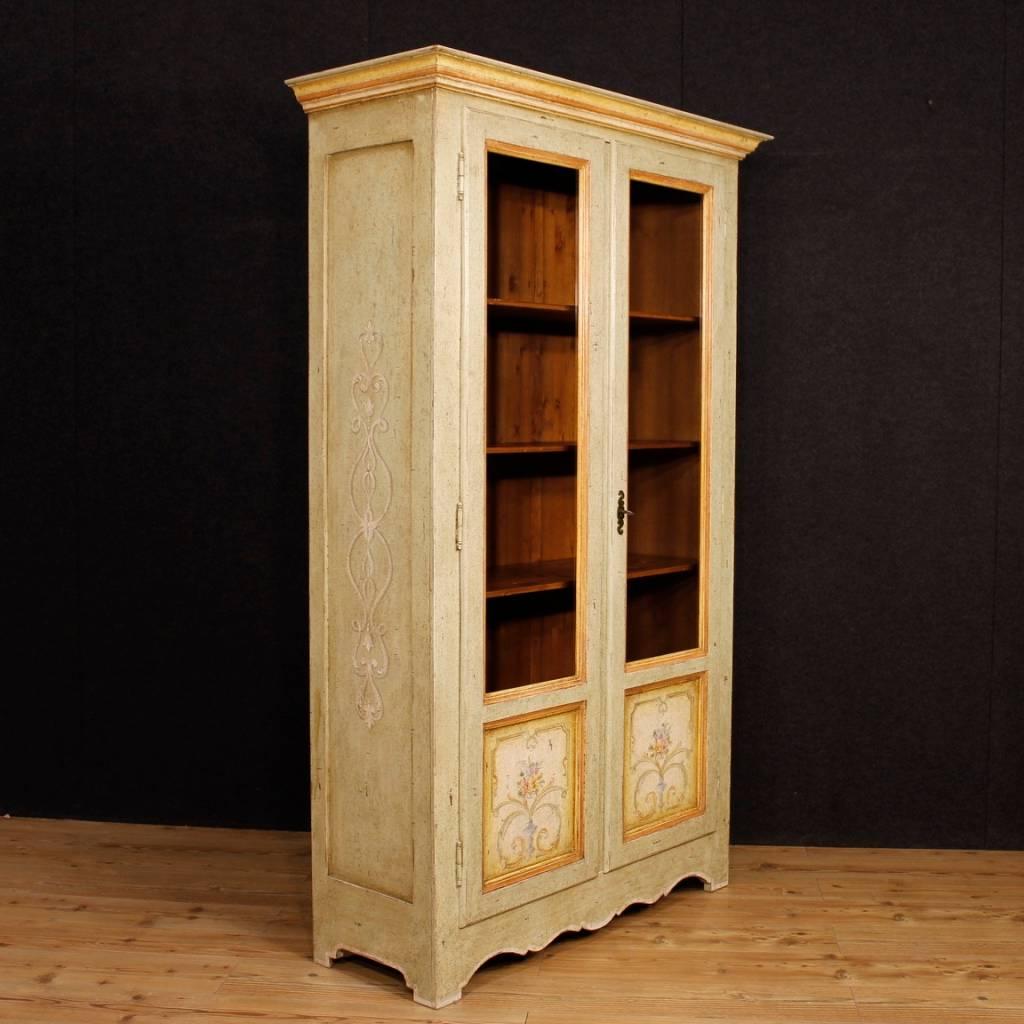 Italian display cabinet of the 20th century. Furniture in lacquered and painted wood with floral decorations. Two-doors bookcase built into a single body ideal to fit in a room or studio. Vitrine with a working key and four internal shelves, of