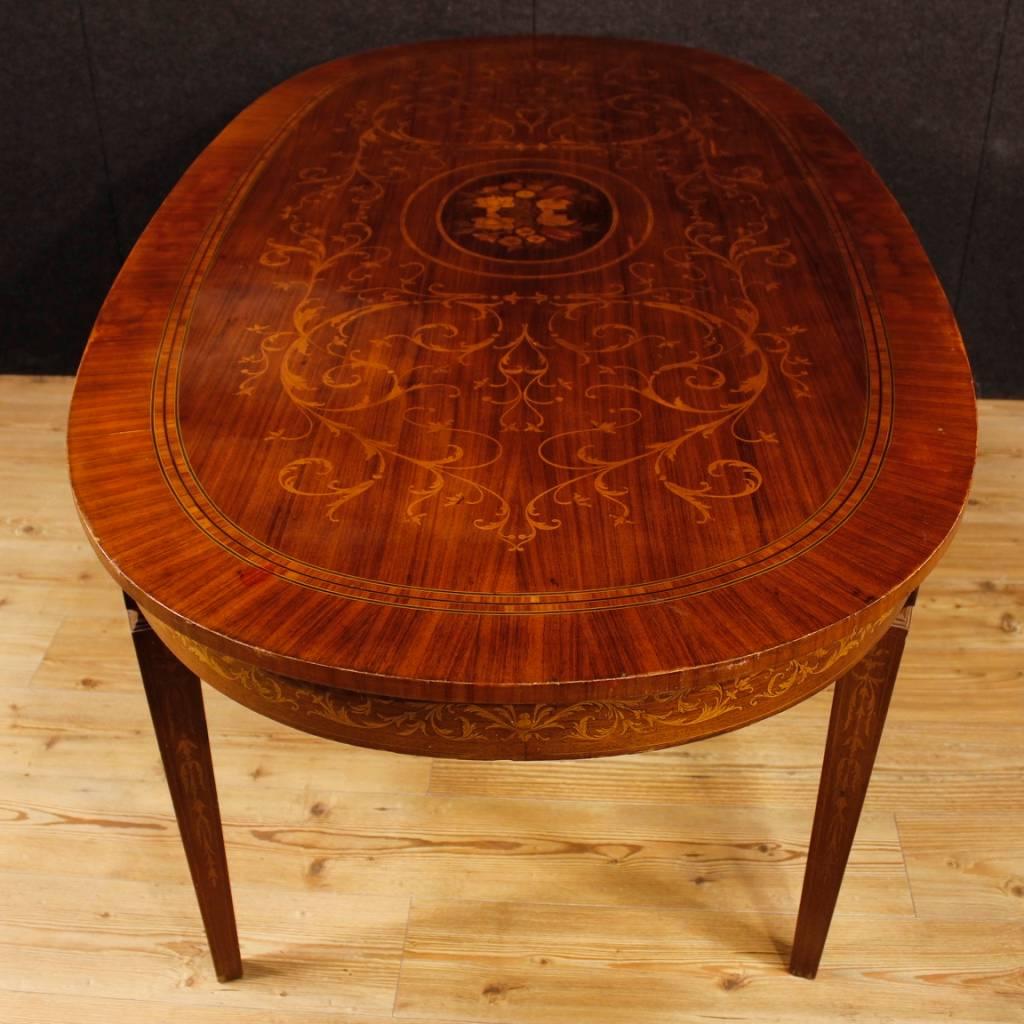 Italian table of the 20th century. Louis XVI style furniture richly inlaid in rosewood, mahogany, walnut, maple and fruitwood with floral decorations. Oval table ideal for a dining room. Furniture supported by four solid legs (also inlaid). Table of