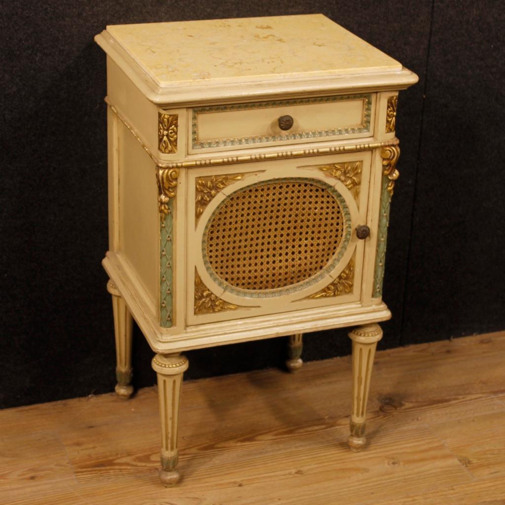 Pair of Italian bedside tables in Louis XVI style from 20th century. Furniture in carved, lacquered and gilded wood with marble top. Bedside tables with one drawer and one door adorned with cane of good capacity and service. Furniture ideal to be