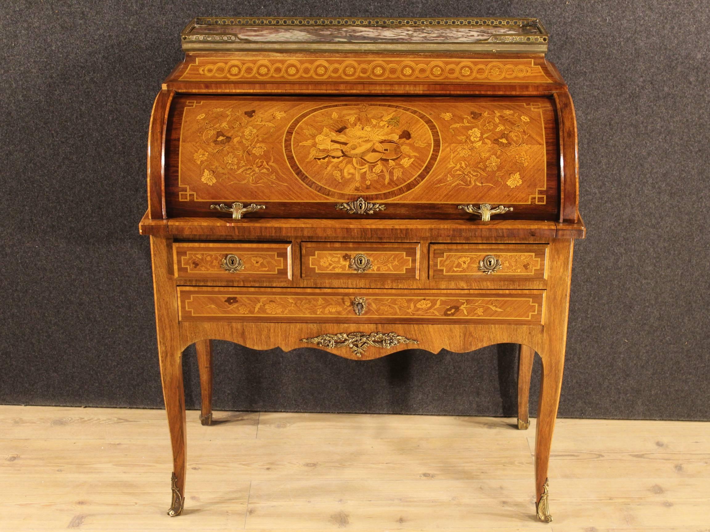 French cylindrical bureau of the 20th century. 
Furniture richly inlaid in rosewood, mahogany, boxwood, maple and fruit woods with floral decorations and musical instruments. Bureau adorned with chiseled bronze in Louis XVI style. Top in marble
