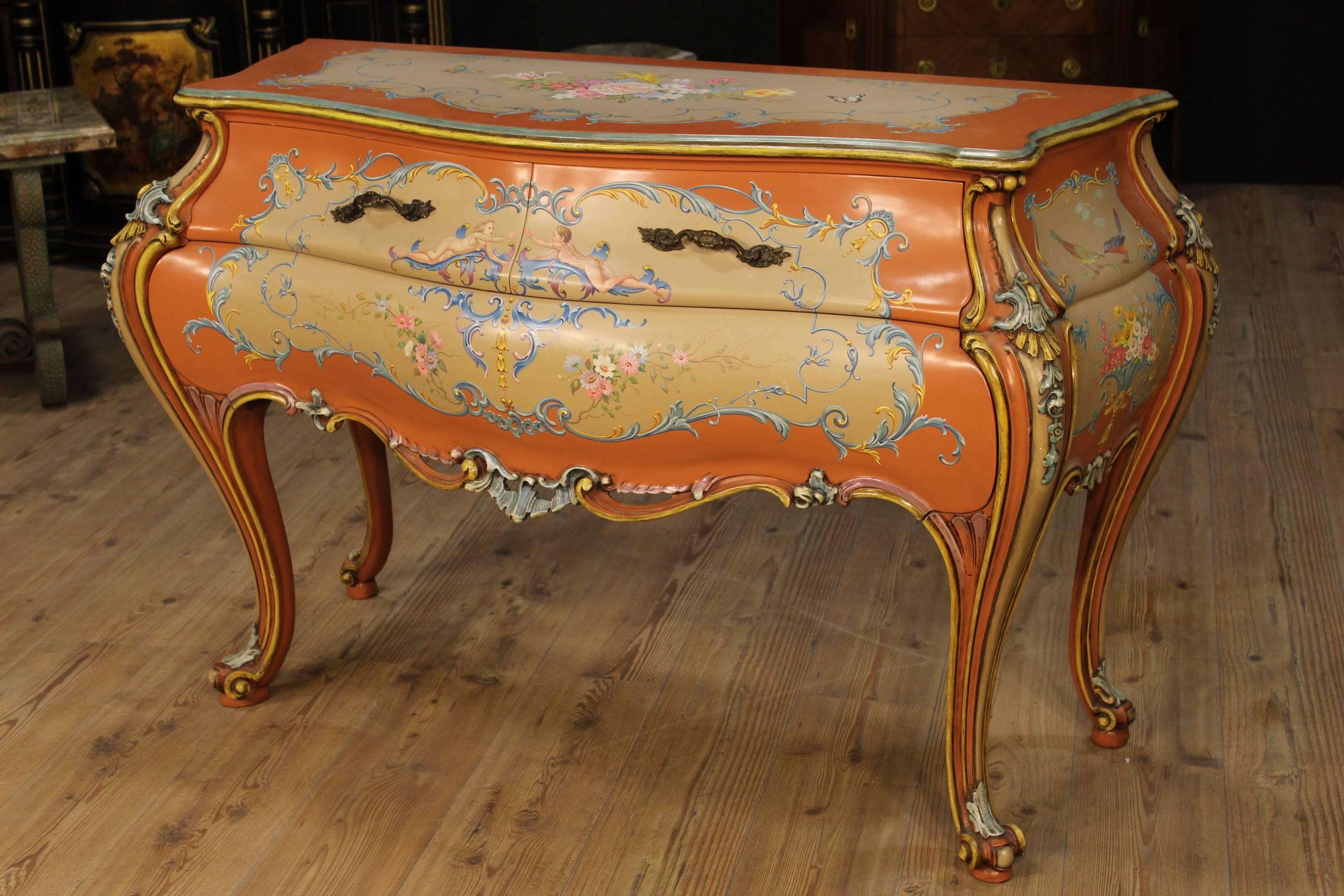 Lacquered Venetian commode. Furniture in ornately carved, lacquered and hand-painted wood with neoclassical decorations and flowers. Dresser with two drawers adorned with chiseled metal handles. Curved commode of the second half of the 20th century.