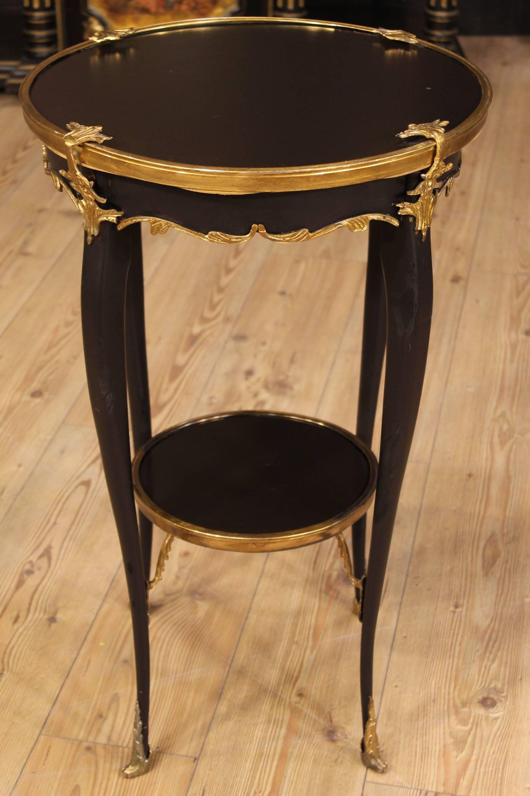 French low table of the 20th century. Furniture of beautiful line and unique design. Coffee table in black lacquered wood decorated with chiseled and gilded bronzes. Table with double shelf. It presents some small signs of the time, on the whole in