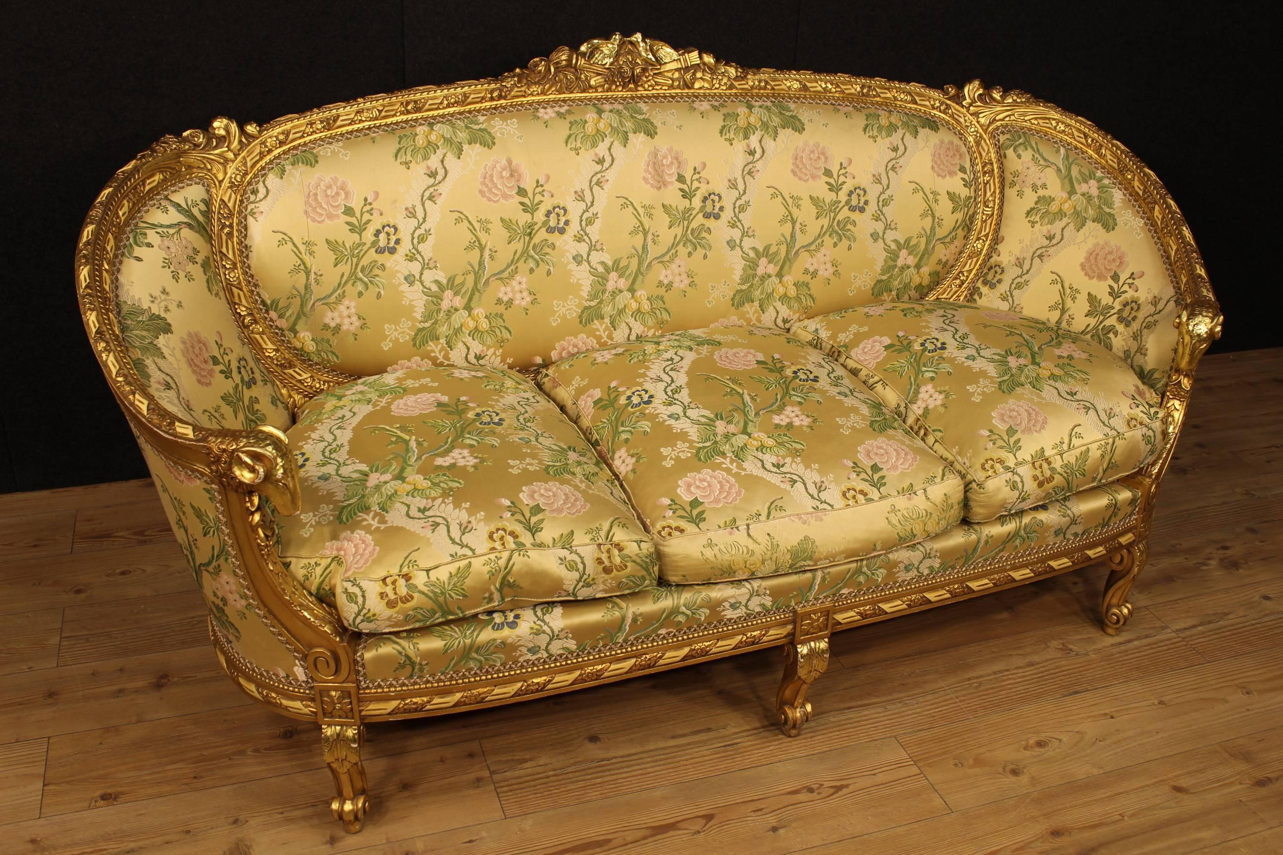 Italian sofa from the second half of the 20th century. Furniture in carved and golden wood with floral and animal motifs. Sofa with padding in good conditions. Floral fabric in good conditions with some small signs. Couch supported by six legs with