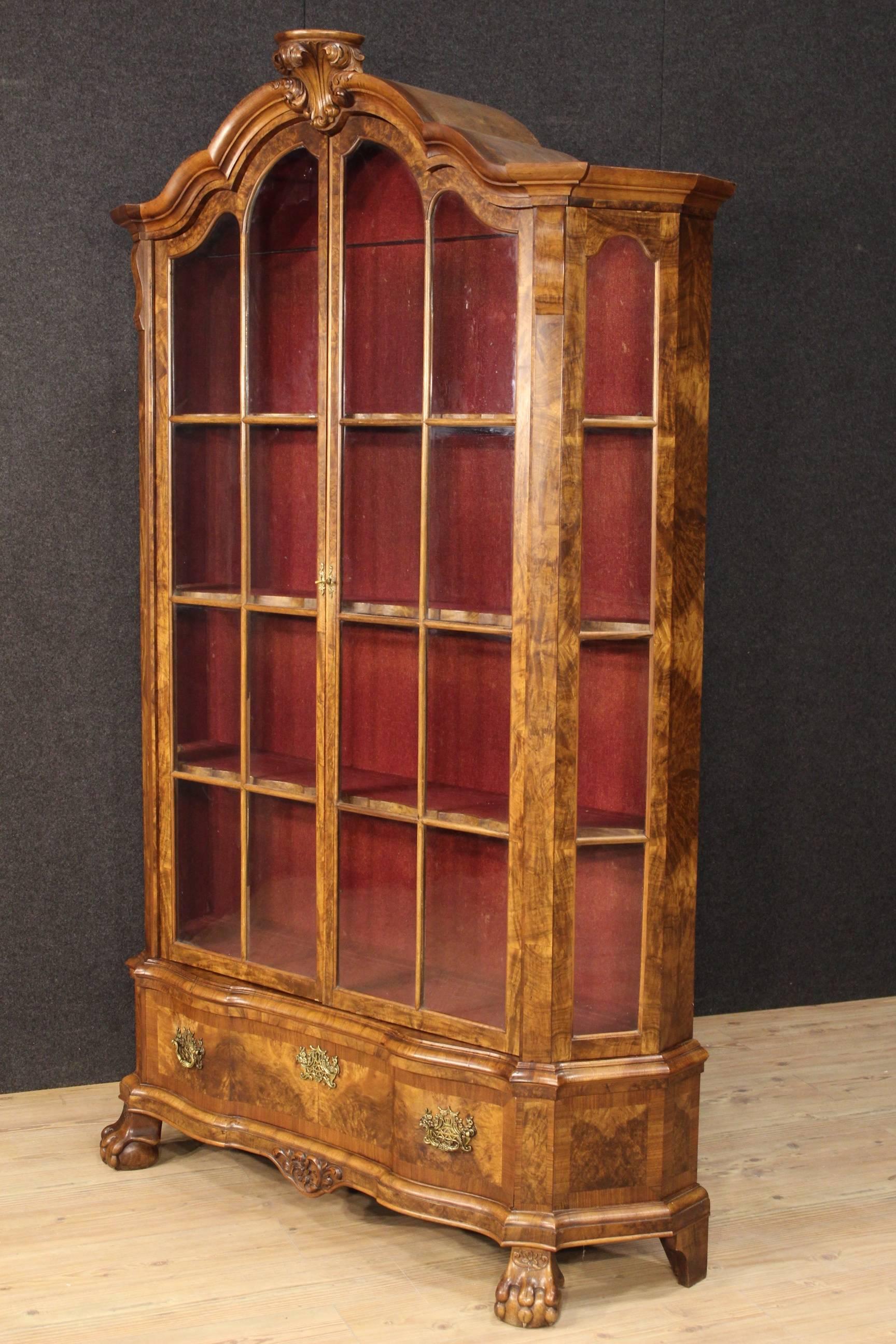 Big Dutch showcase of the 20th century. Furniture carved and veneered in walnut, burl and mahogany. Bookcase with two large doors, complete with a working key, plus a lower drawer, missing key. Furniture supported by four feet of which two frontal