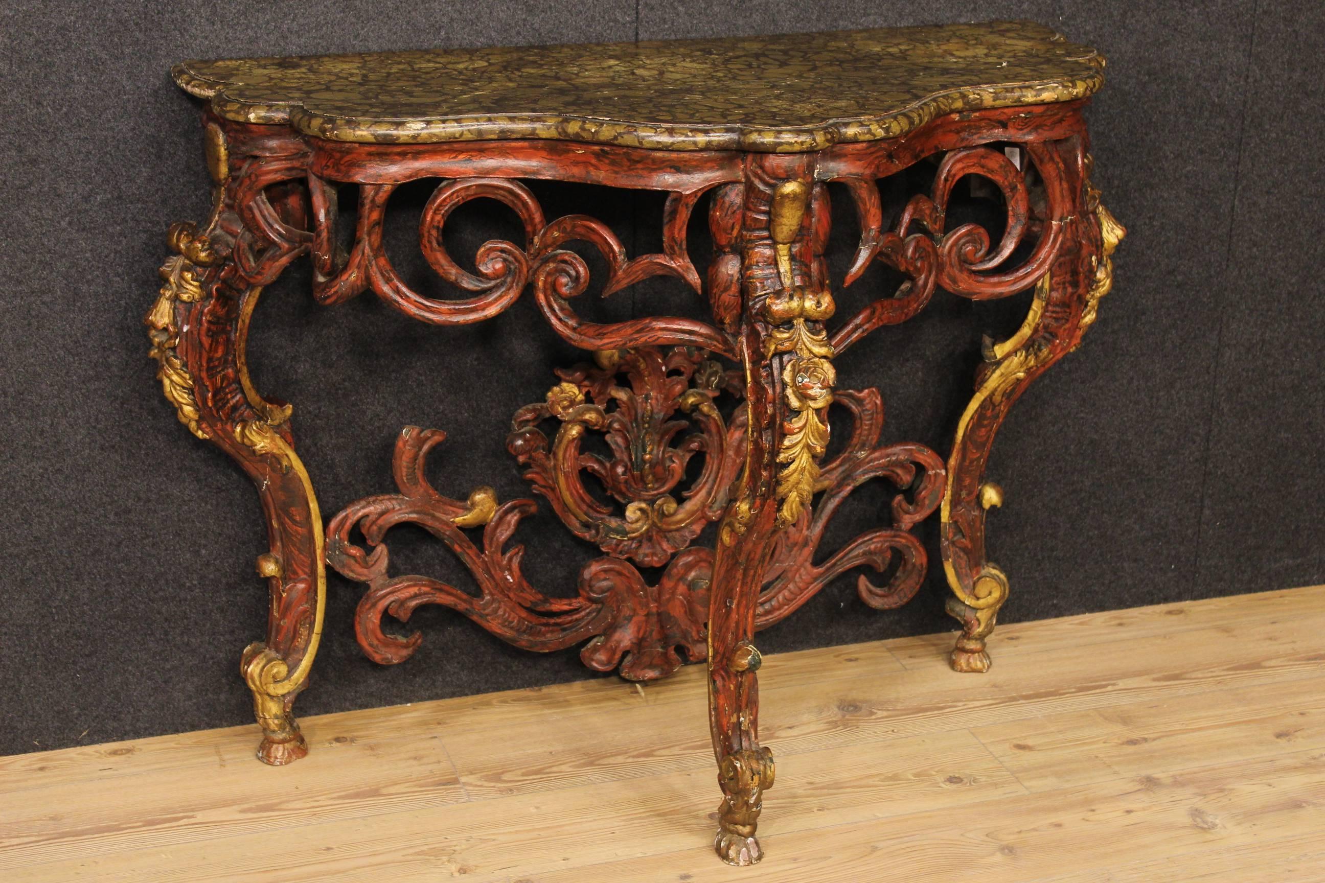Scenographic Italian console table built with ancient parts. Carved, lacquered and gilded furniture made by wood. Wall console table with top made by lacquered wood and fake marble. Furniture built with legs and ancient top of the 19th century. Band