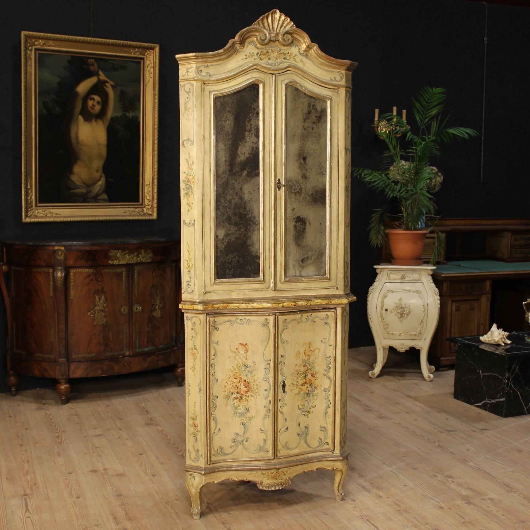 Antique Venetian corner cupboard of the 19th century. Double body furniture finely carved, lacquered and hand painted with floral decorations. It presents original mercury mirrors and a working key for both doors. Interior of the corner cupboard