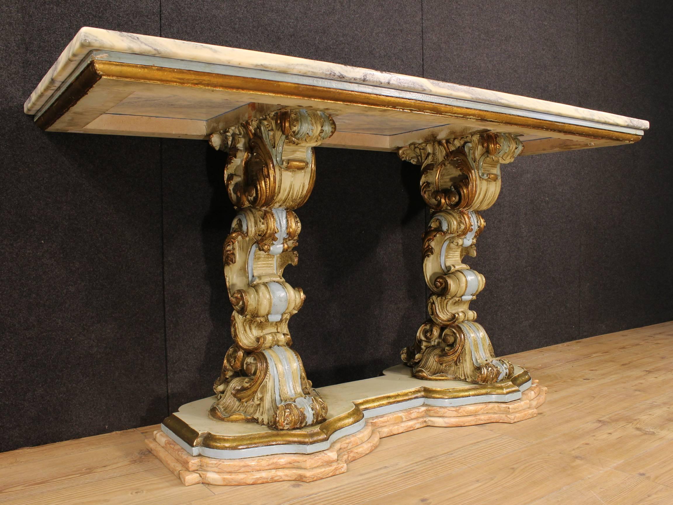 Scenic Florentine console table of the second half of the 20th century. Furniture made by ornately carved, gilded and lacquered wood. It has a base of pink marble. Top in cipolin marble in excellent condition. Console table that can also be used as