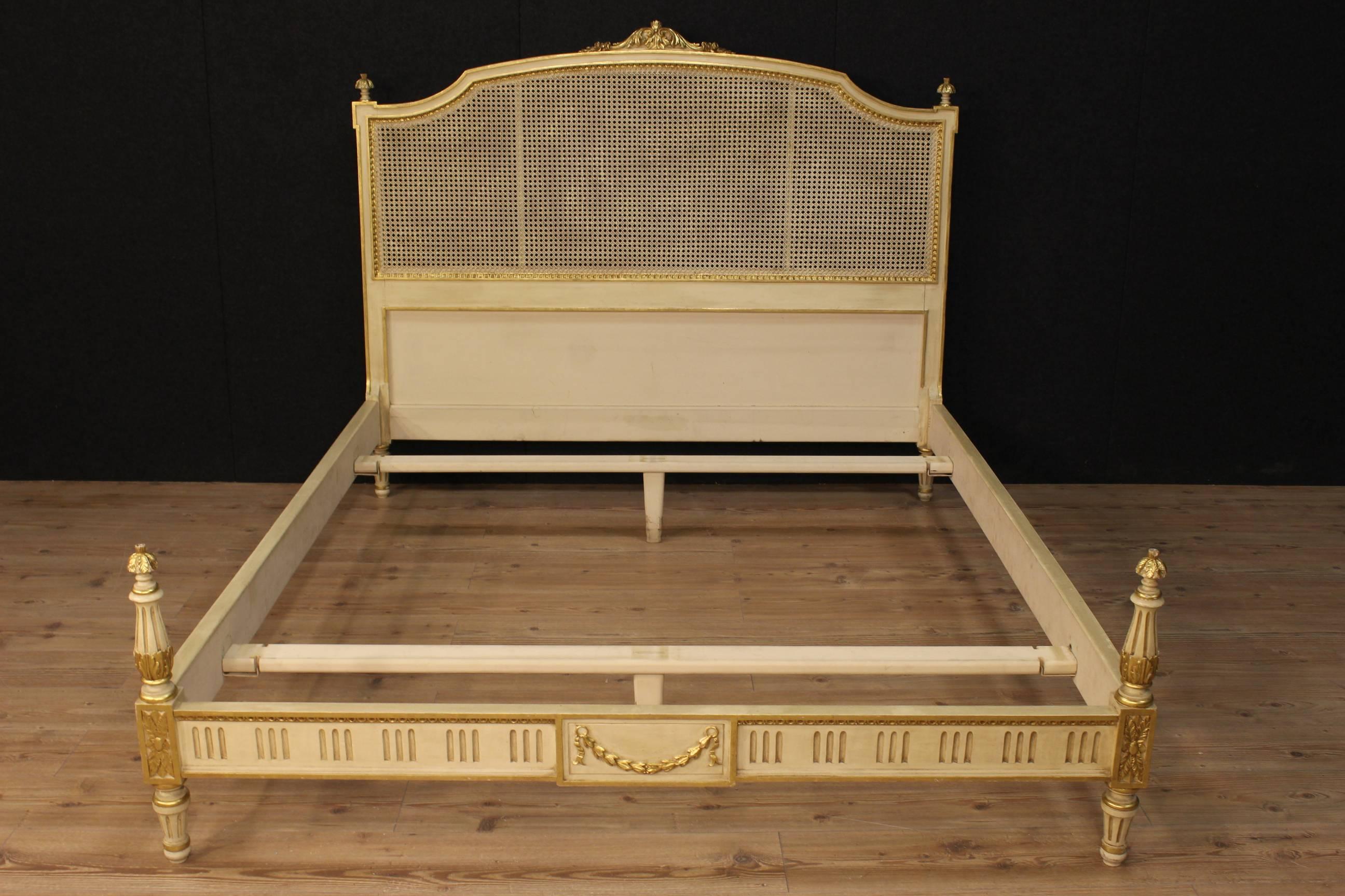 Elegant Italian bed of the 20th century. Furniture made by ornately carved, lacquered and gilded wood in Louis XVI style of great taste and beautiful decoration. Double bed of great extent and impact with headboard decorated with cane in perfect